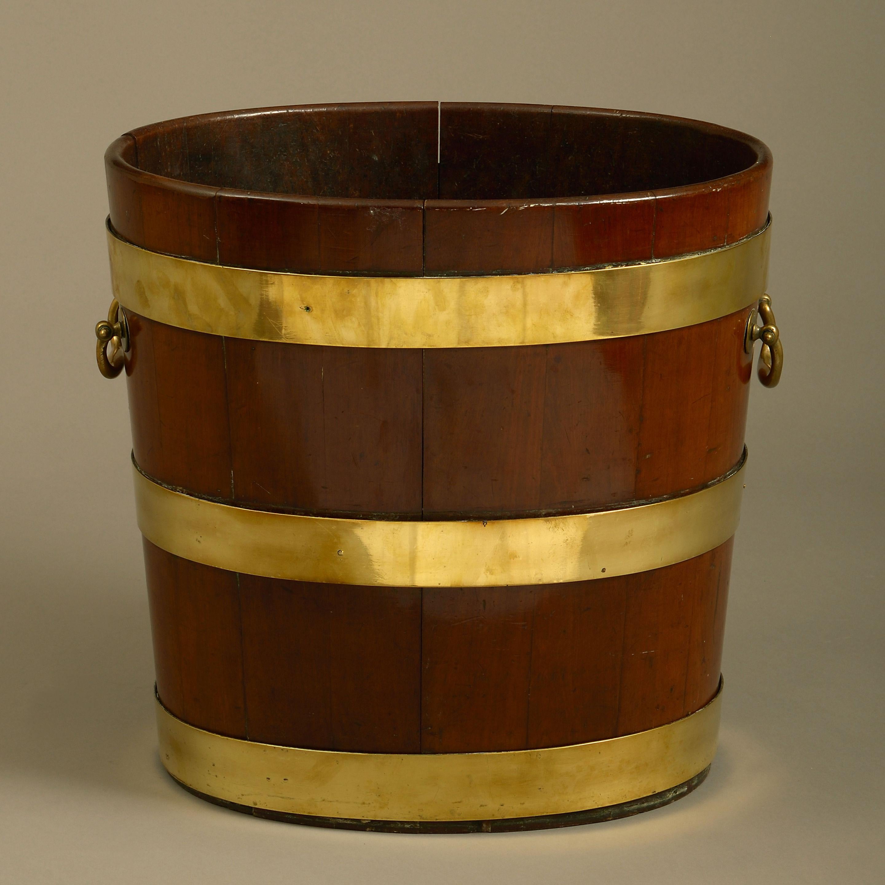A large late 18th century brass bound and coopered mahogany peat bucket, of oval form, retaining the original carrying handles.
