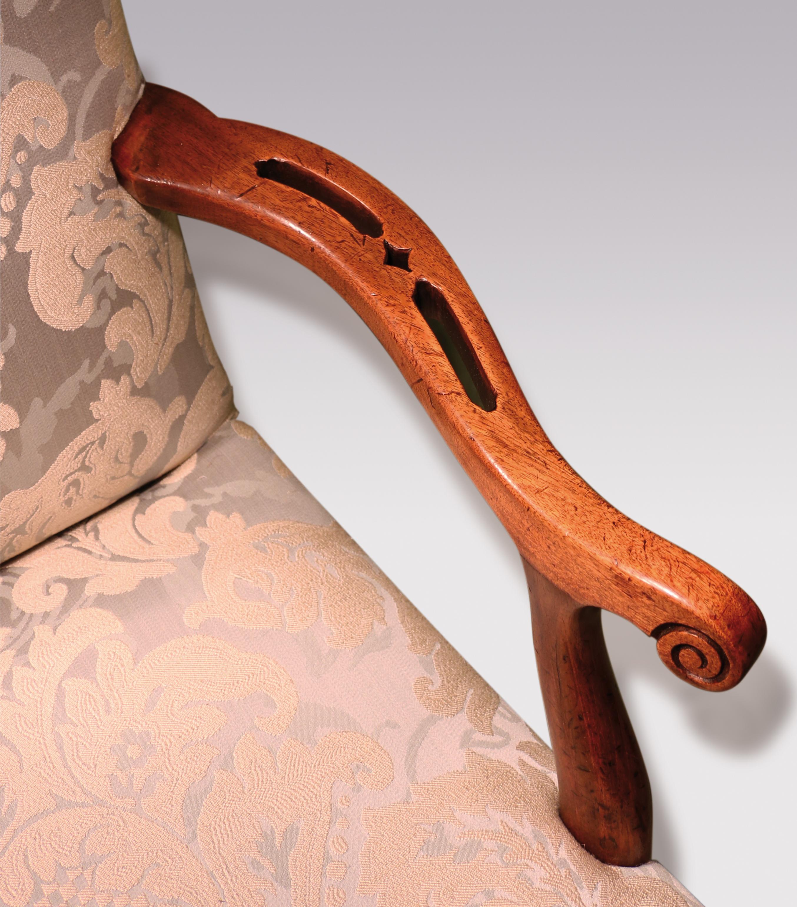 A mid-18th century George III period mahogany Gainsborough chair of attractive small proportions, having serpentine top-rail above shaped scrolled set-back arms with unusual fret piercings, supported on chamfered blind-fret legs joined by pierced