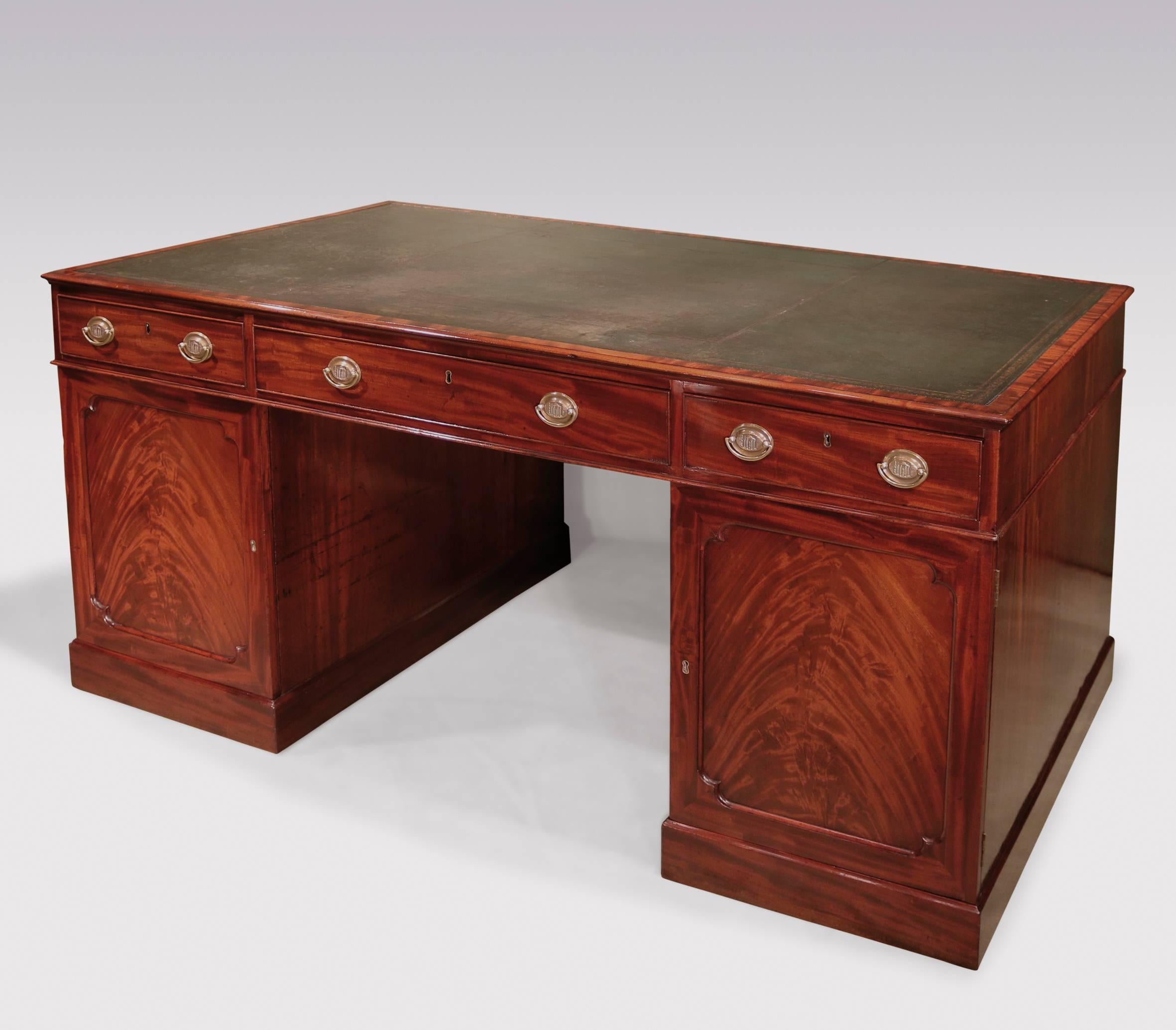 A fine late 18th century well figured mahogany library partner’s desk, having gilt tooled green leather moulded edge top, above six cockbeaded drawers. The desk, having further graduated drawers to the front and flame figured paneled cupboard doors