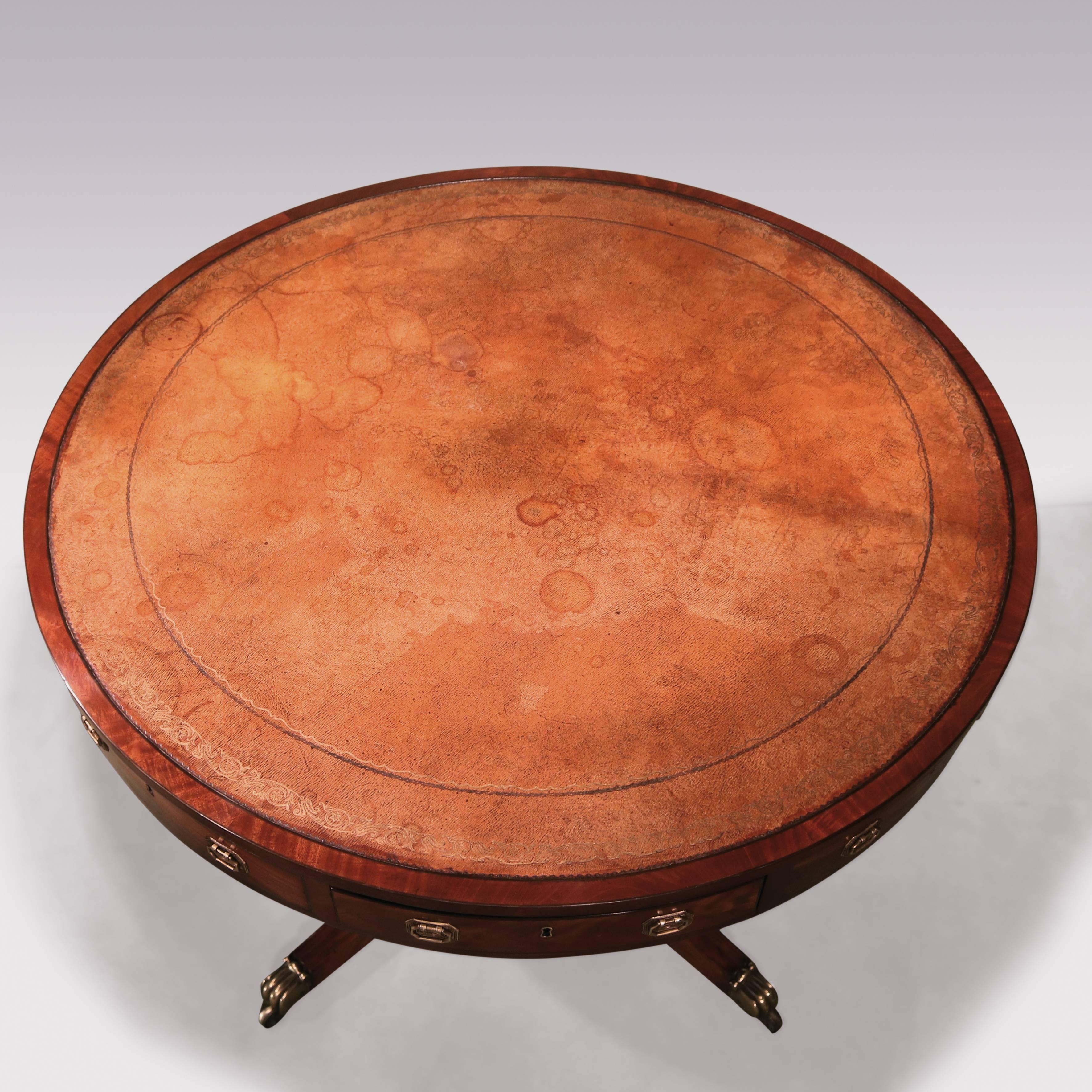 A George III period mahogany revolving drum table, ebony strung throughout, having four real and four dummy flame-figured drawers, raised on baluster turned stem, supported on moulded four -spaly legs, ending on original brass lion's paw castors.