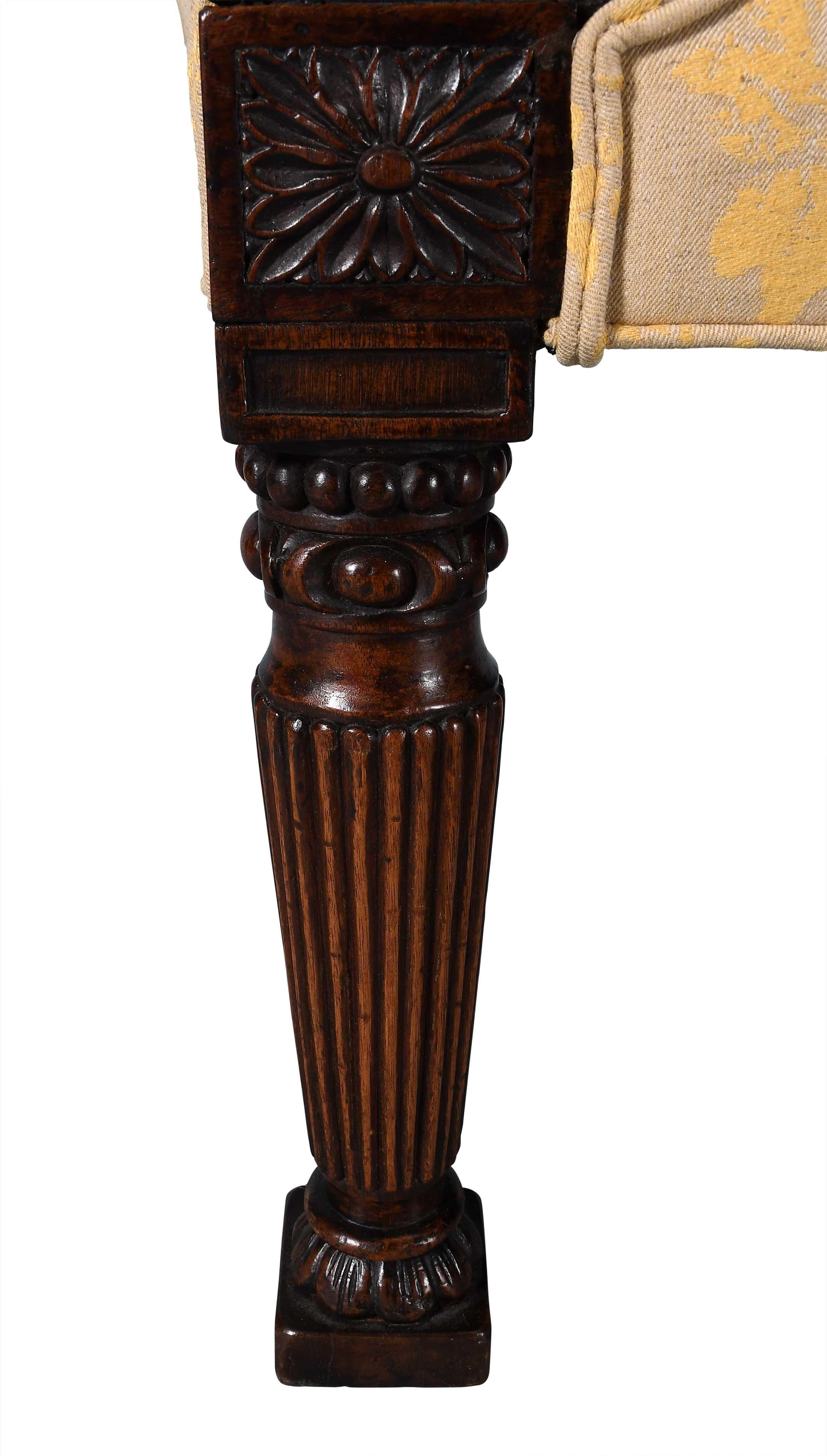 A fine quality window bench with scrolled ends. The show-wood portions of the ends are carved with a leaf motif terminating in a rosette at each end. The tapering, reeded legs end in bold block feet and are capped by rectangular rosettes. Perfect