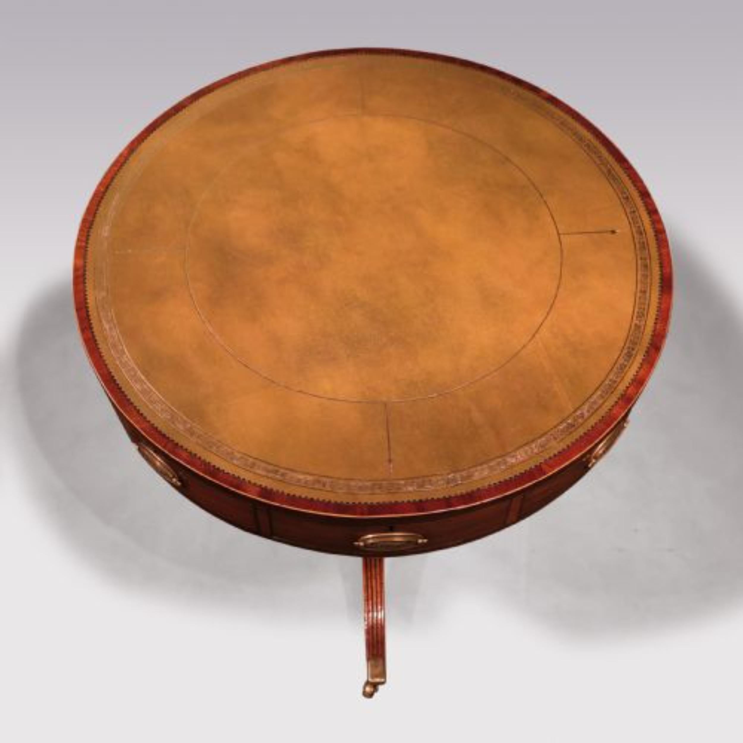 A George III period mahogany revolving Library Drum Table of attractive small proportions, having faded green leather gilt tooled boxwood strung crossbanded circular top, above 4 real & 4 dummy drawers raised on elegant gun-barrel stem & reeded 3
