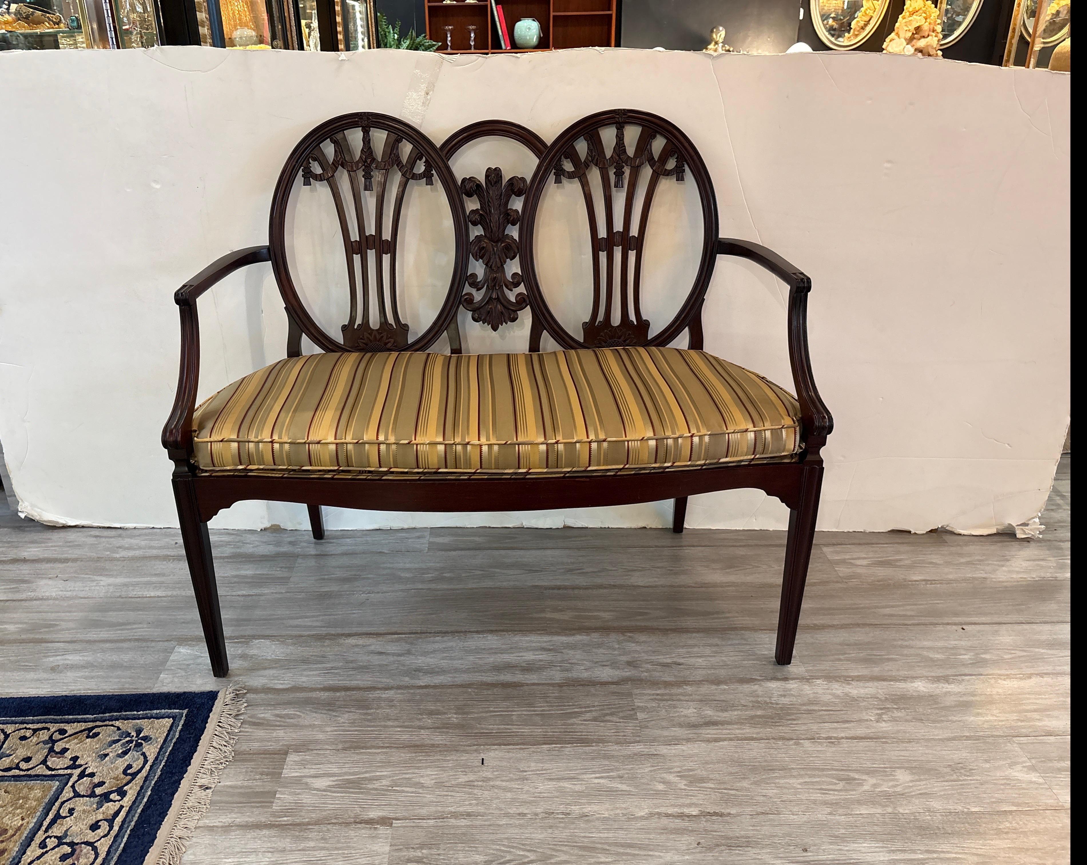 An elegant hand carved mahogany George III double frame back settee.  The oval backs with plume spalt in center with gently formed ridge arms and tapering legs. The seat in 100% new silk stripe.  