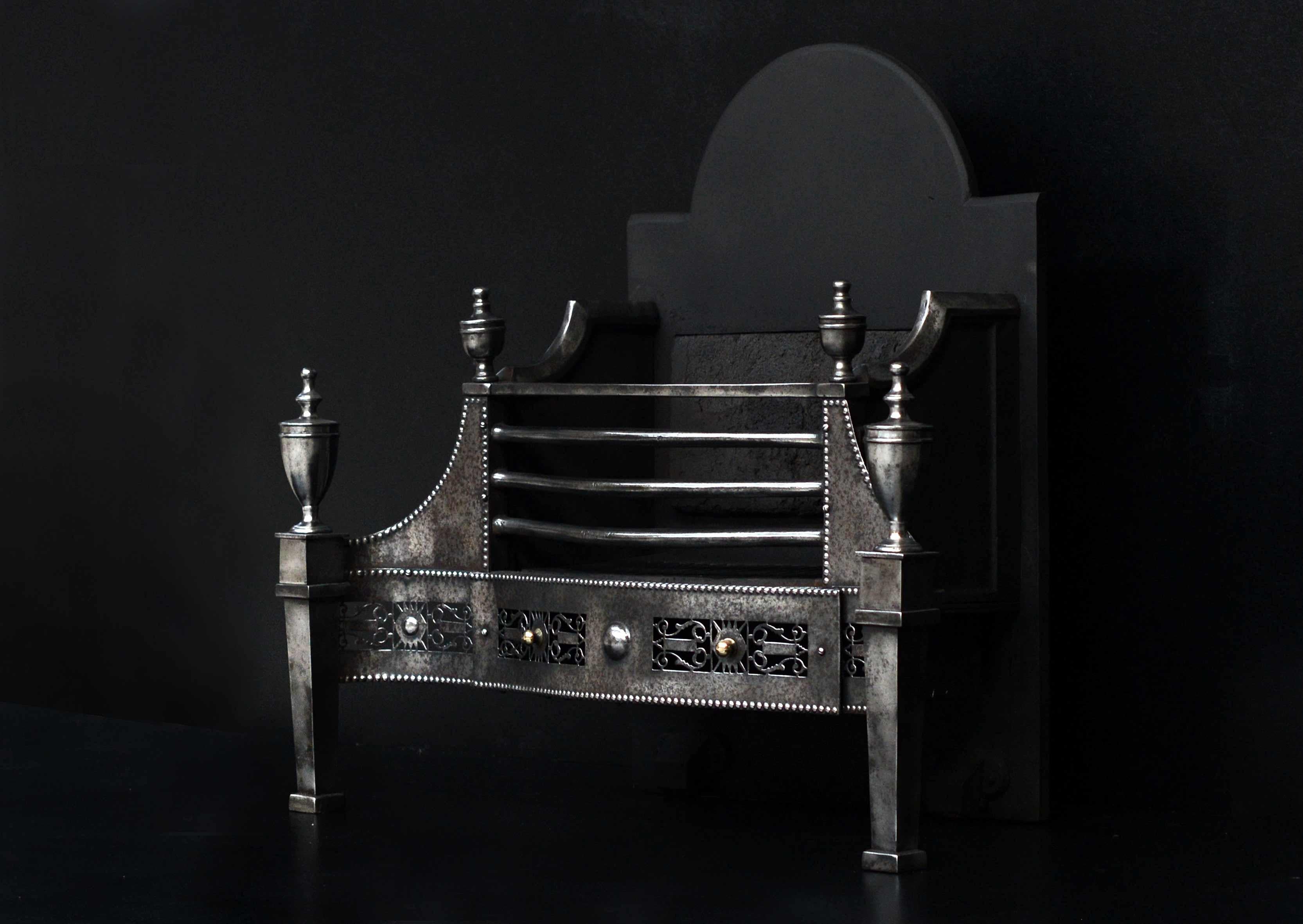 An attractive English George III style steel firegrate. The finely pierced serpentine fretwork of lyre design, tapered legs surmounted by urn finials. Shaped frontbars and shaped backplate. Late 19th century.

Width At Front:	850 mm      	33
