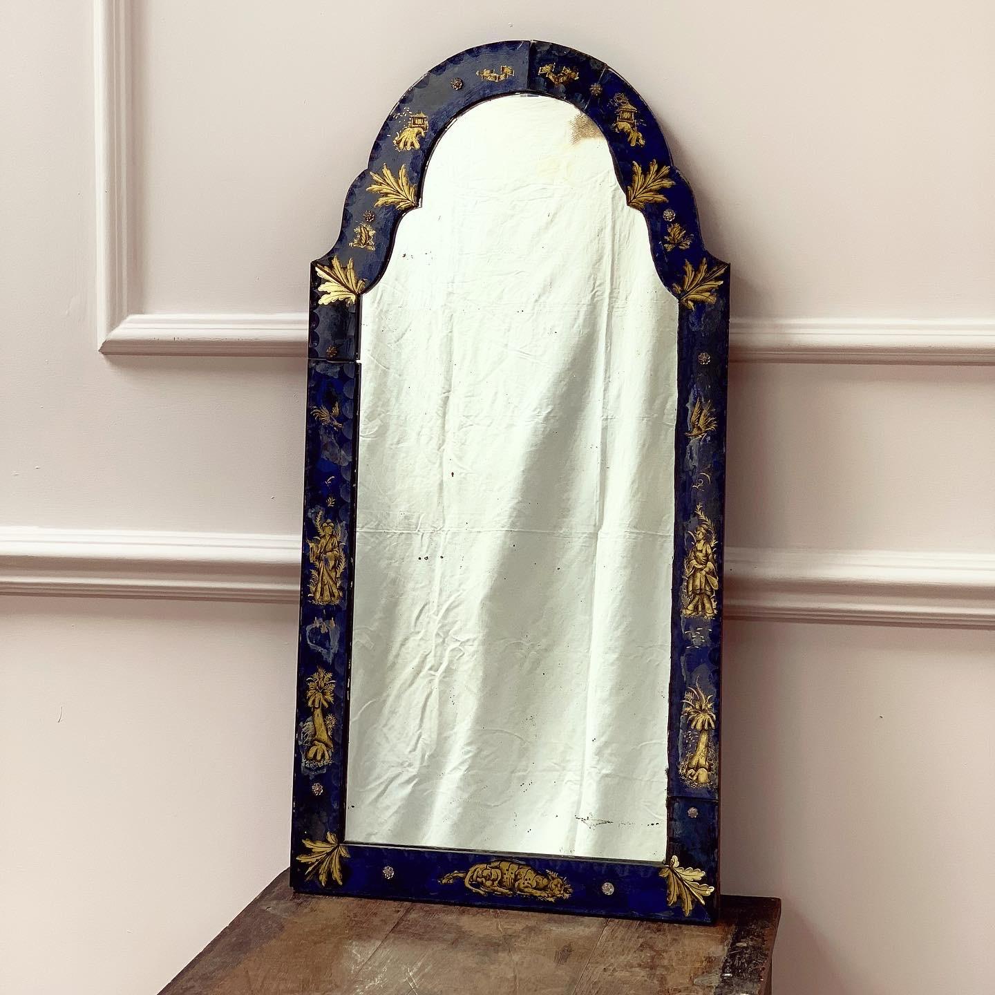 A George III verre eglomise pier mirror with arched mirror plate in a glass frame depicting gilt chinoiserie female figures, animals and leaves on a cobalt blue ground.