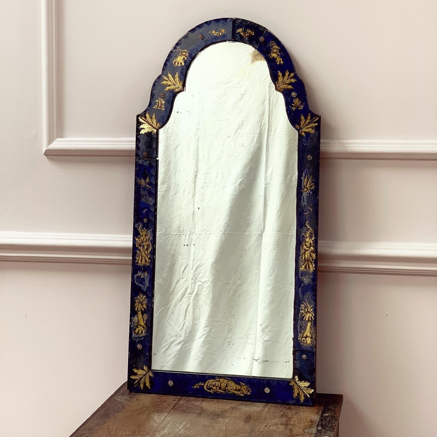 Miroir en verre églomisé de George III avec plaque de miroir arquée dans un cadre en verre représentant des figures féminines, des animaux et des feuilles en chinoiserie dorée sur un fond bleu cobalt.
