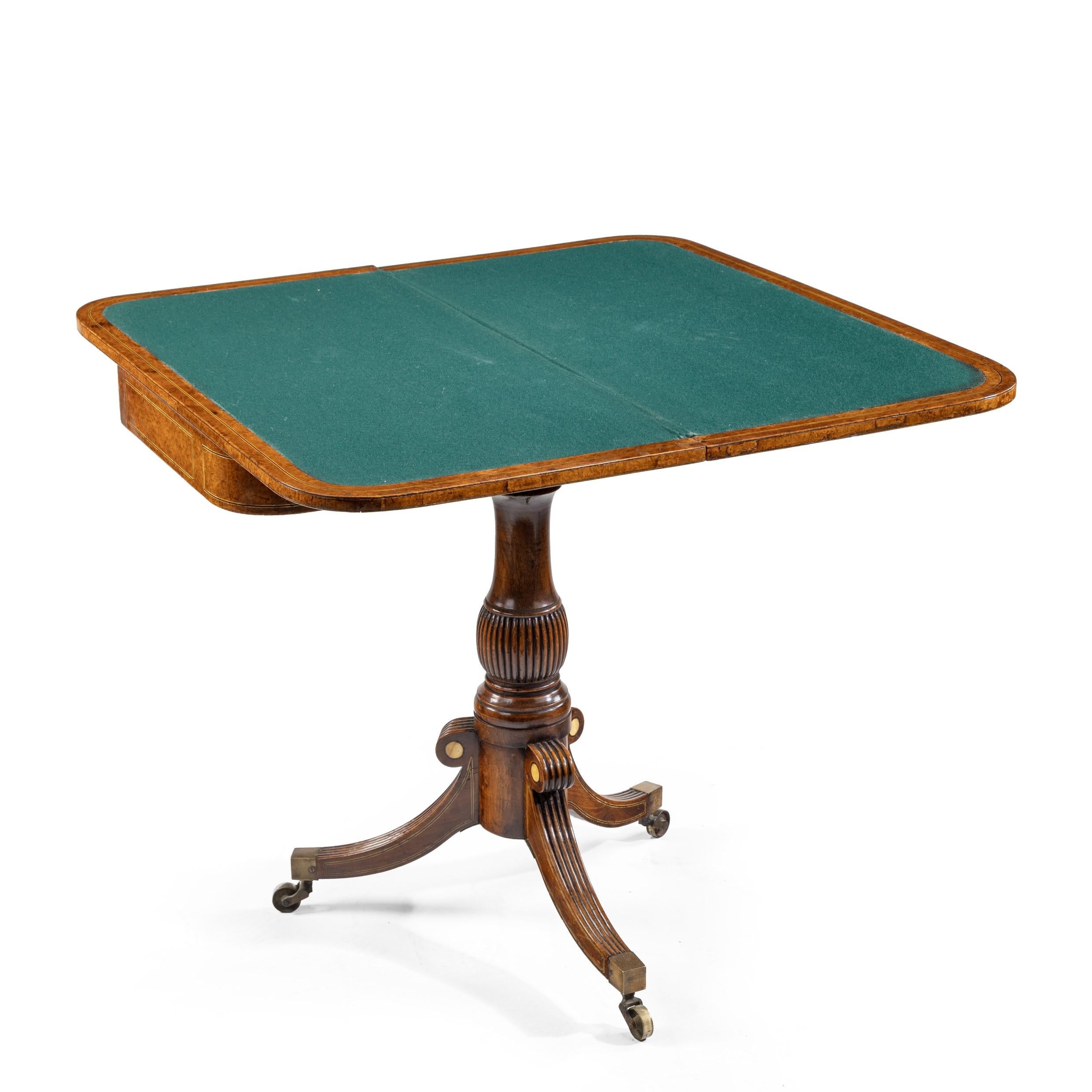 A George IV Anglo-Chinese amboyna card table, the hinged rectangular top with rounded corners opening out to form a square, lined in later green baize, decorated with bone and ebony strung panels, raised on a solid rosewood gadrooned and turned