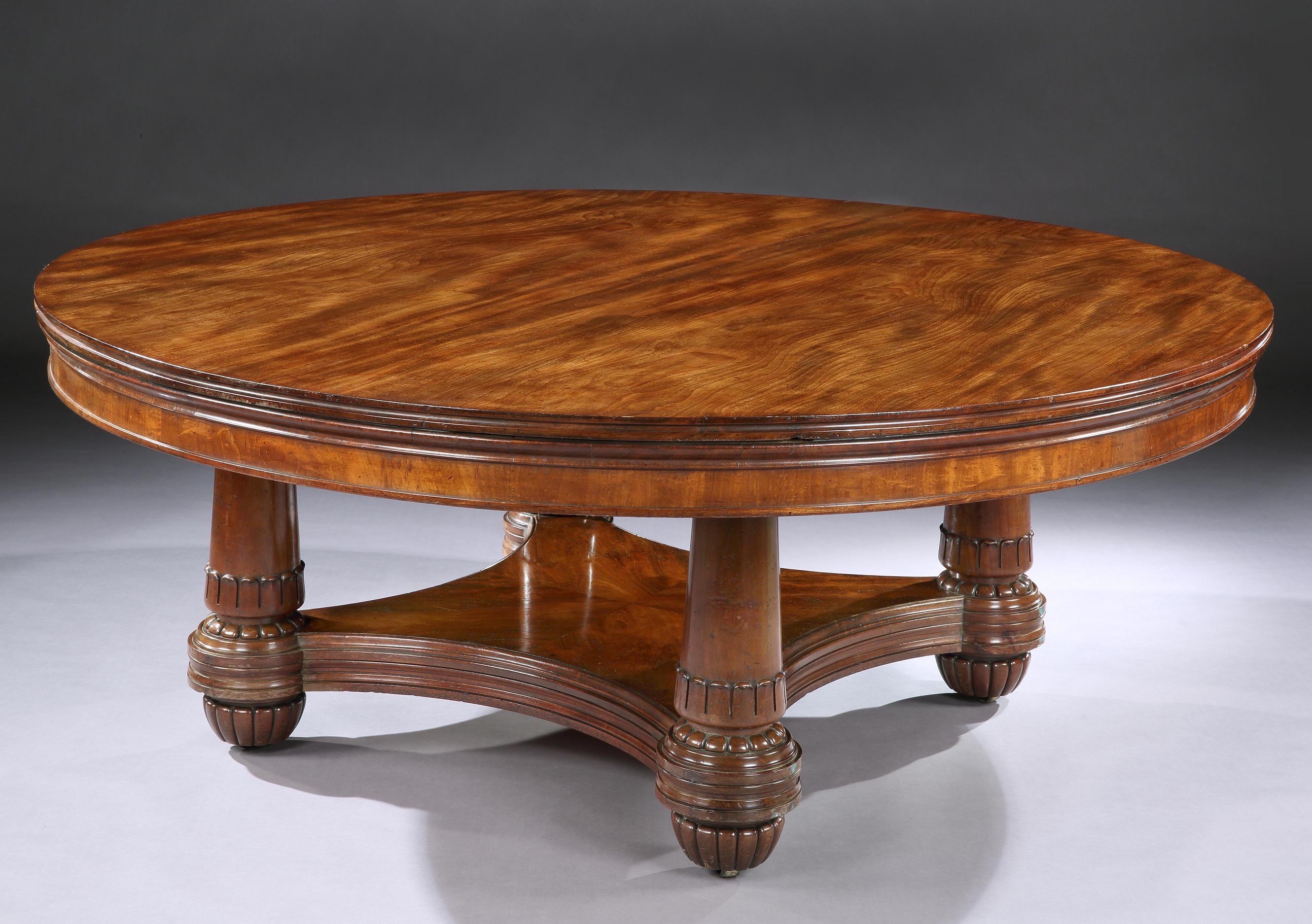 A superbly figured mahogany round extending table, the top with a double moulded edges, with six extending leaves, resting on four turned acanthus carved pillar supports, sitting on a plate-form base, with a treble moulded edge, resting on four
