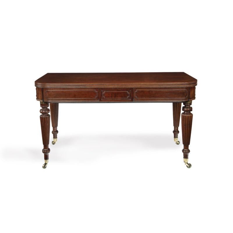 This mahogany dining table is of rectangular form with rare hinged D-ends, swivel top and reeded edge.  It extends on an ingenious and complex action, with various levers and locks, which accommodates five additional leaves.  The frieze has outline