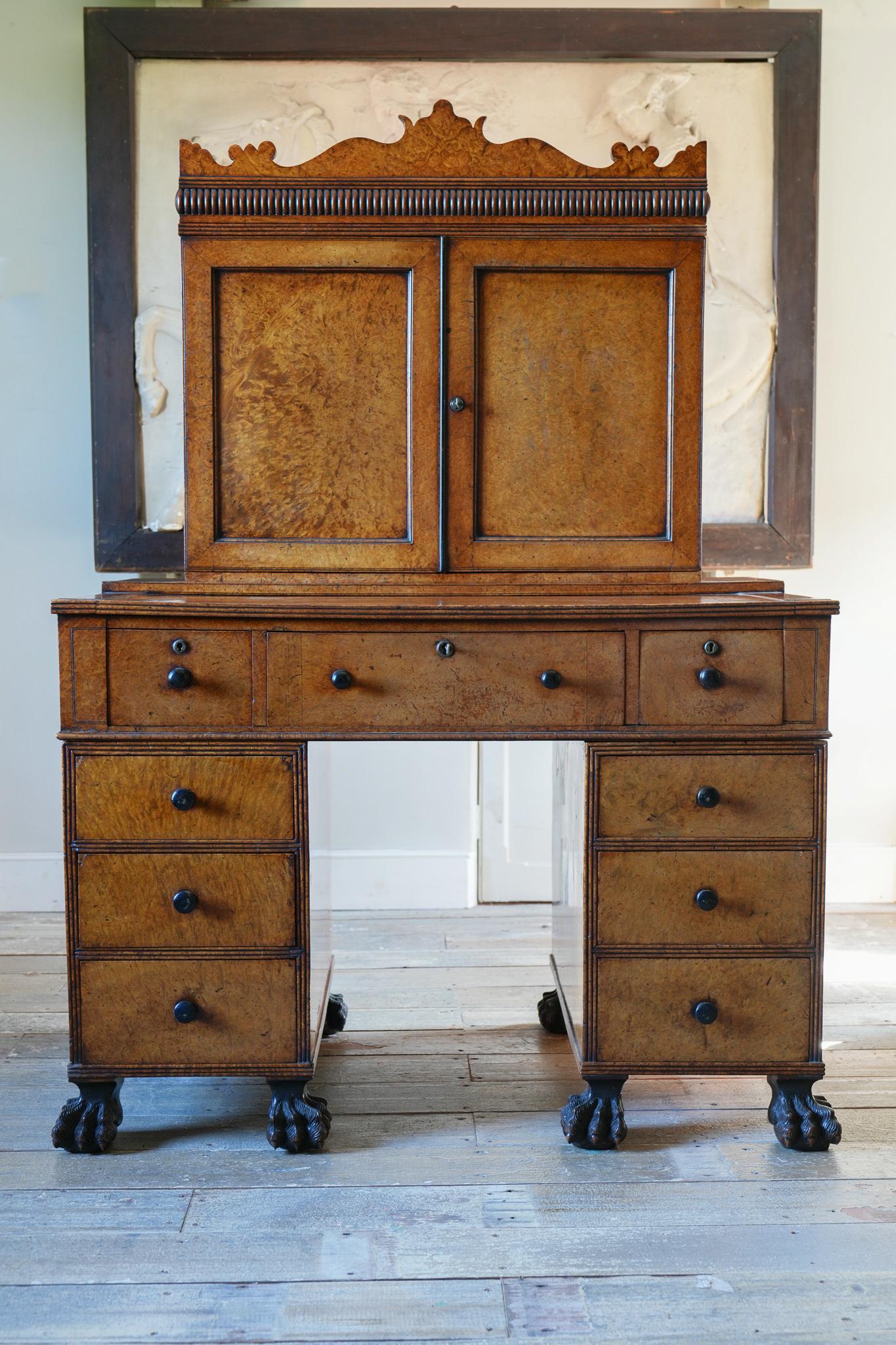 The shaped cornice above a fitted bureau-bookcase enclosed behind solid doors, the central desk drawer has a ratcheted writing slope and is flanked by three graduated drawers to each pedestal, all drawers have their original turned ebony handles,