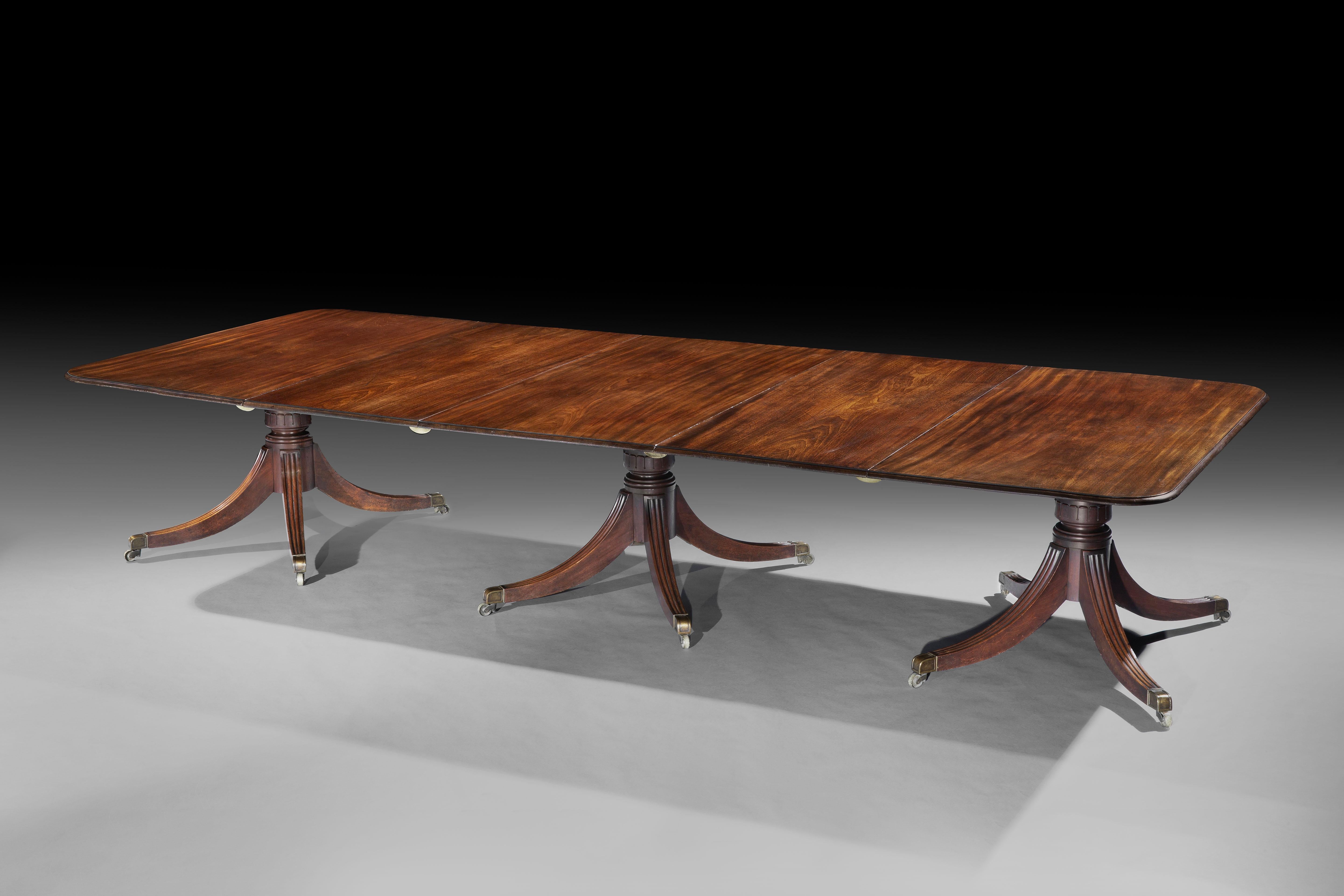 A Fine George IV Mahogany Dining Table

The rectangular figured mahogany top with a moulded edge,
retaining a superb original finish, with two extra leaves,
resting on three column supports, with carved lotus leaf stems
and four shoot of reeded