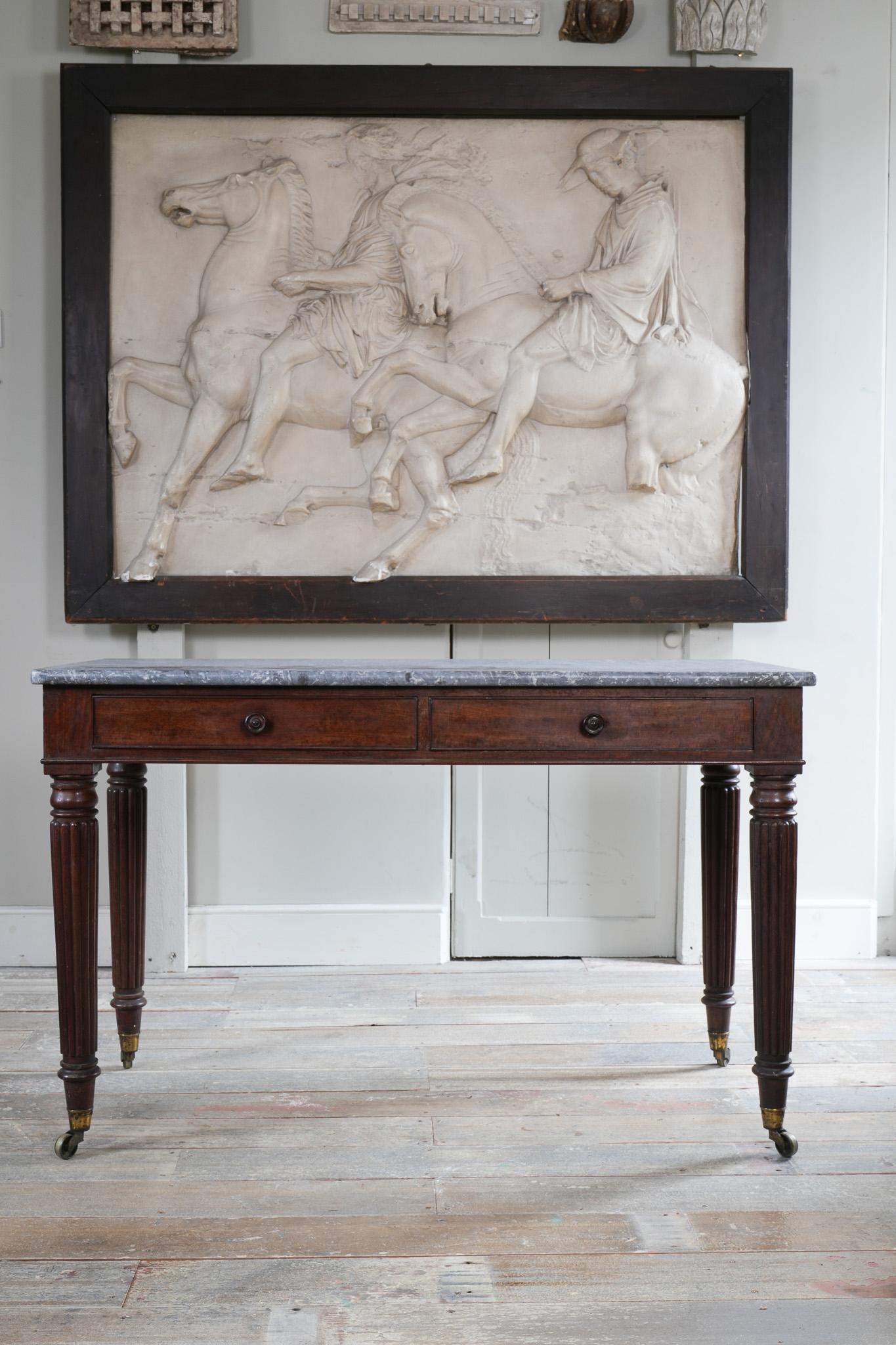 The marble top above twin frieze drawers with turned handles, raised on tapering reeded leg with original brass castors.

In the manner of Gillows.