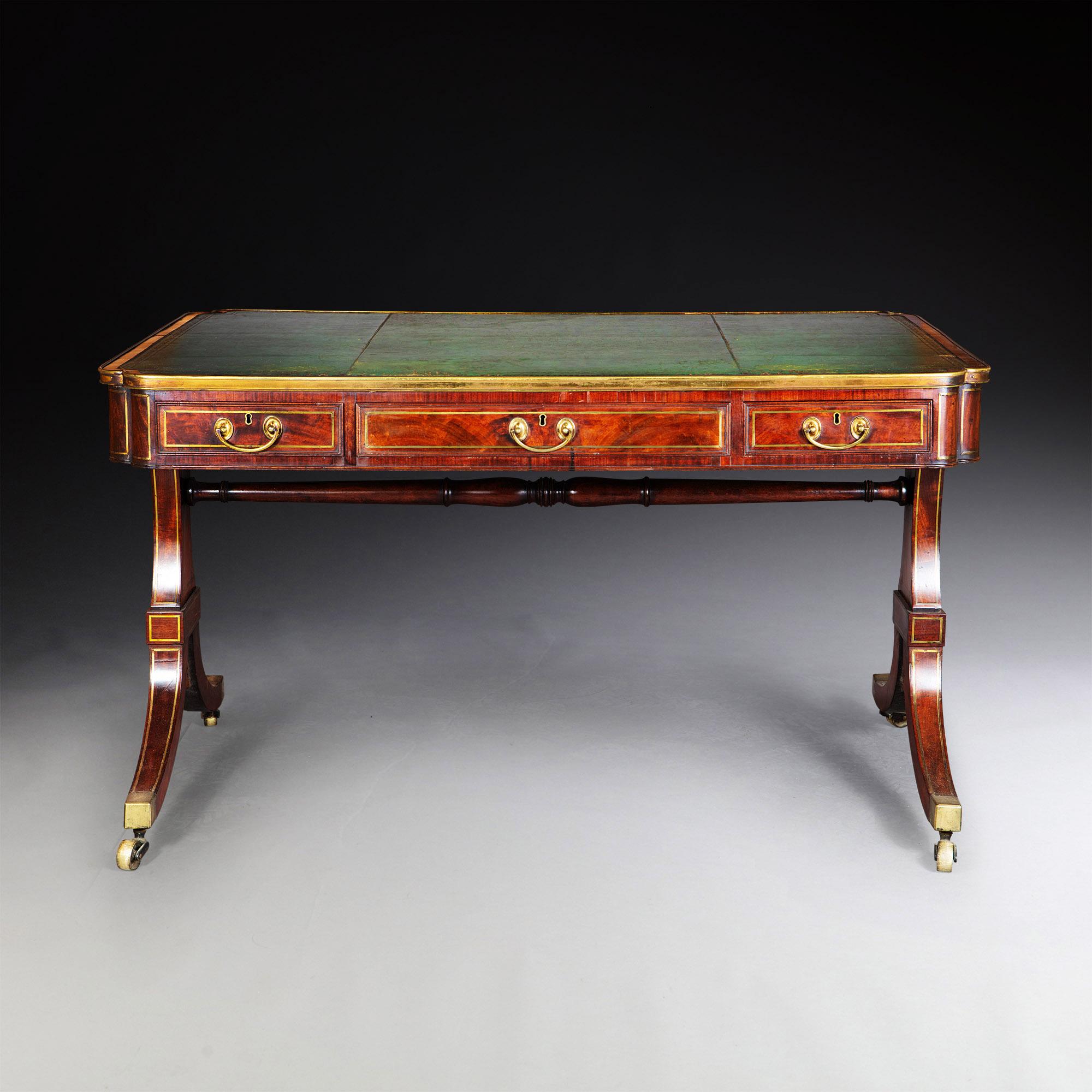 A fine George IV figured mahogany writing table
The tooled leather top inside a mahogany band, with a double brass rimed edge, above a frieze with two brass rimmed drawers. Features panel sides in figured mahogany, resting on solid brass inlaid