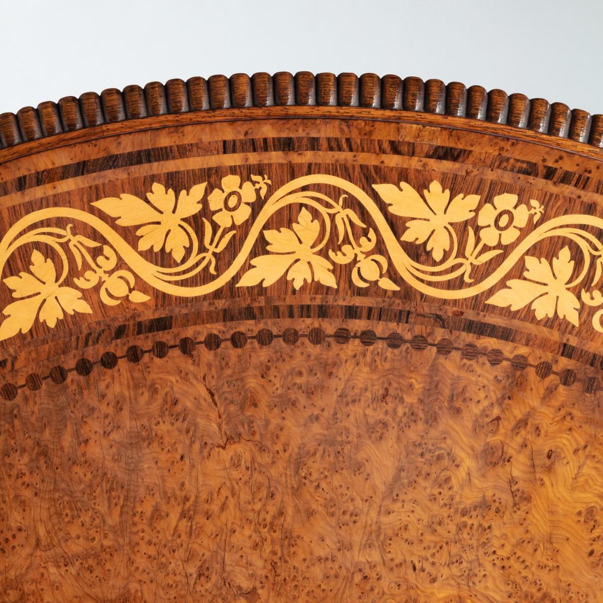 Table centrale à plateau basculant de George IV par George Bullock, le plateau circulaire avec un champ d'amboine centré sur un cercle de chêne brun, d'ifs et de houx, la bordure décorée d'un méandre floral en bois de roi dans des bandes et des