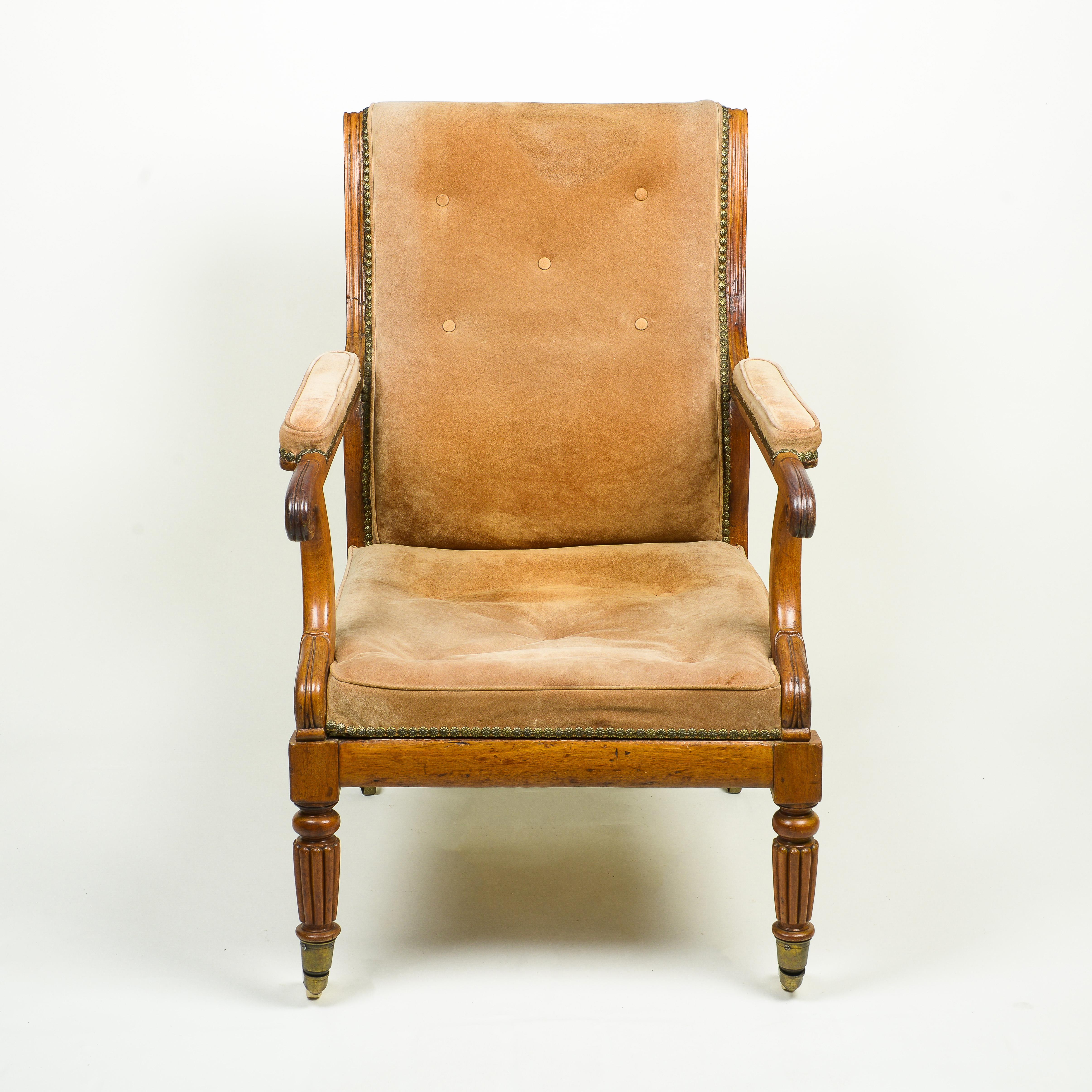 The rectangular slanted back upholstered with tufted suede with nailhead trim, issuing padded armrests terminating in scrolls; the suede overupholstered seat over a deep seat rail; raised on turned and reeded tapering front legs terminating in brass
