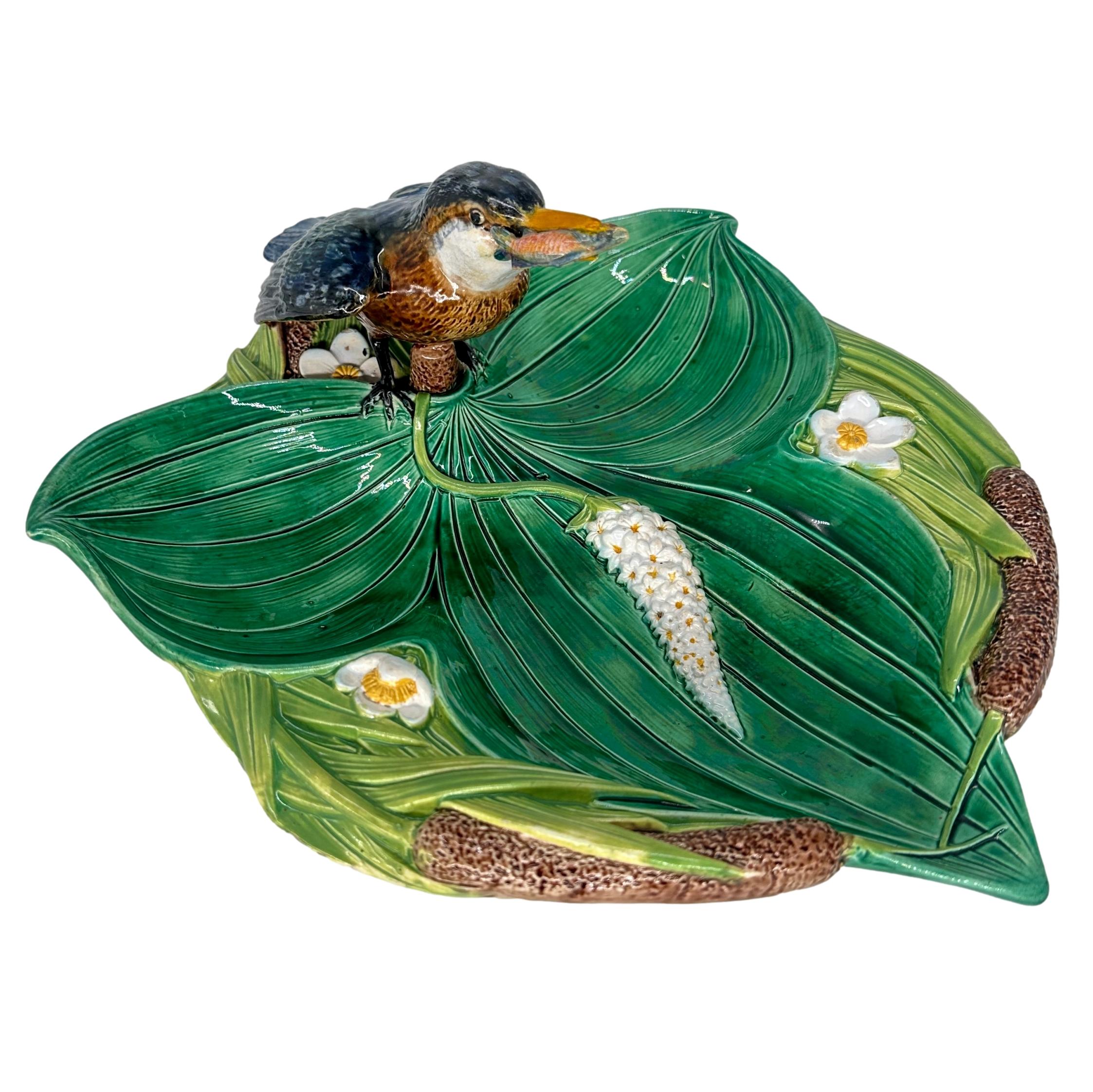 Bandeja de majolica George Jones con forma de martín pescador sobre nenúfar. El plato tiene forma de trébol y está moldeado naturalmente como un nenúfar y flores con espadañas, con un modelo esmaltado de un martín pescador con un pez en el pico, la