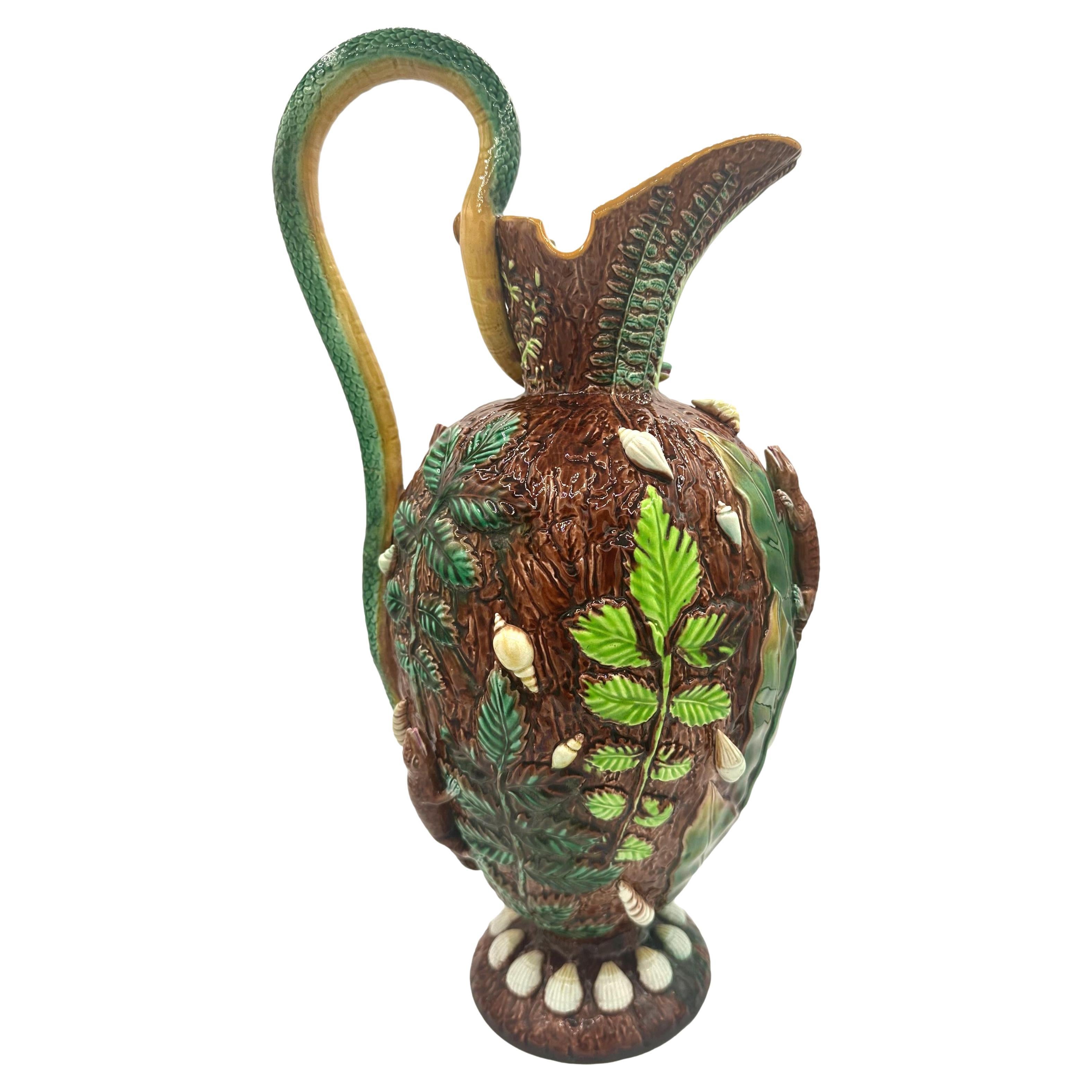 A Highly Important George Jones Majolica 'Palissy Vase,' molded as an obovoid-form ewer, the rustic bark ground with molded green-glazed leaves and ferns, molded and applied with three naturalistic lizards and seashells on a mound-form base