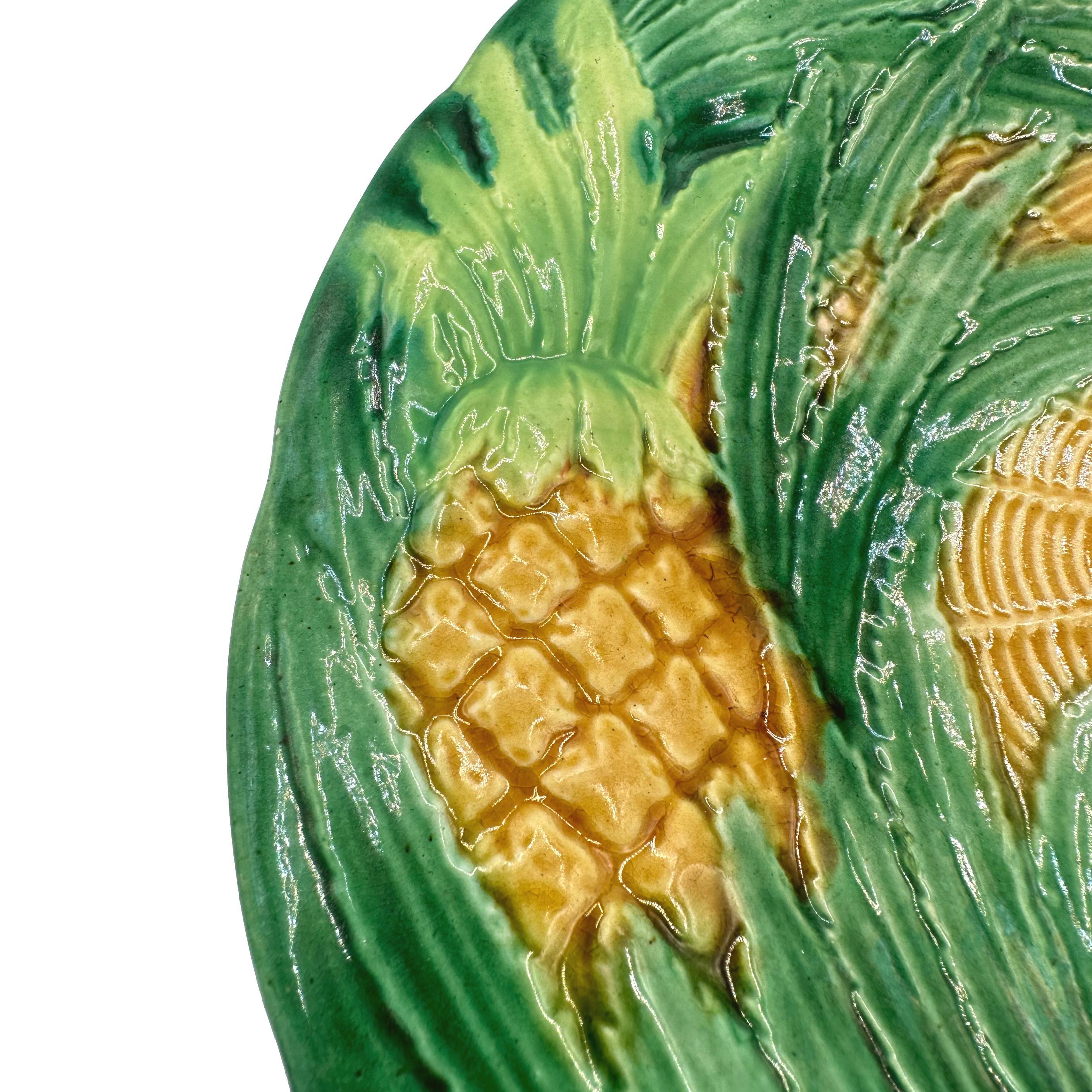 A George Jones Majolica Dessert Plate, with relief-molded pineapples and swirling green-glazed leaves, the center with yellow ocher-glazed simulated basketweave, English, ca. 1870.  Design number 1419. 
LITERATURE:
Robert Cluett, GEORGE JONES