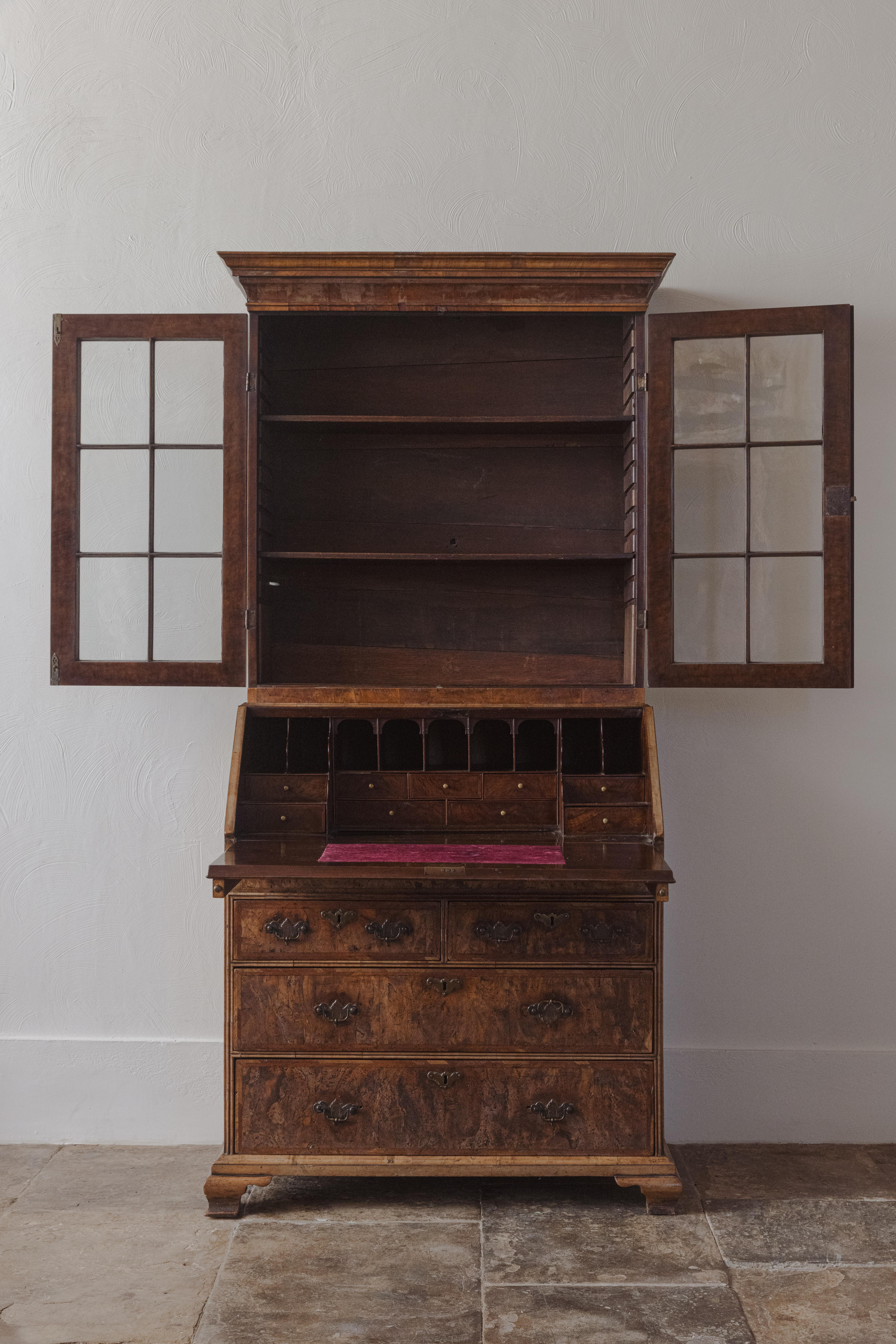 Charmante bibliothèque-bureau en ronce de noyer du début de l'époque géorgienne, avec des portes vitrées d'origine sur une façade à abattant et un intérieur aménagé, au-dessus de deux tiroirs courts et de deux tiroirs longs sur des pieds d'origine