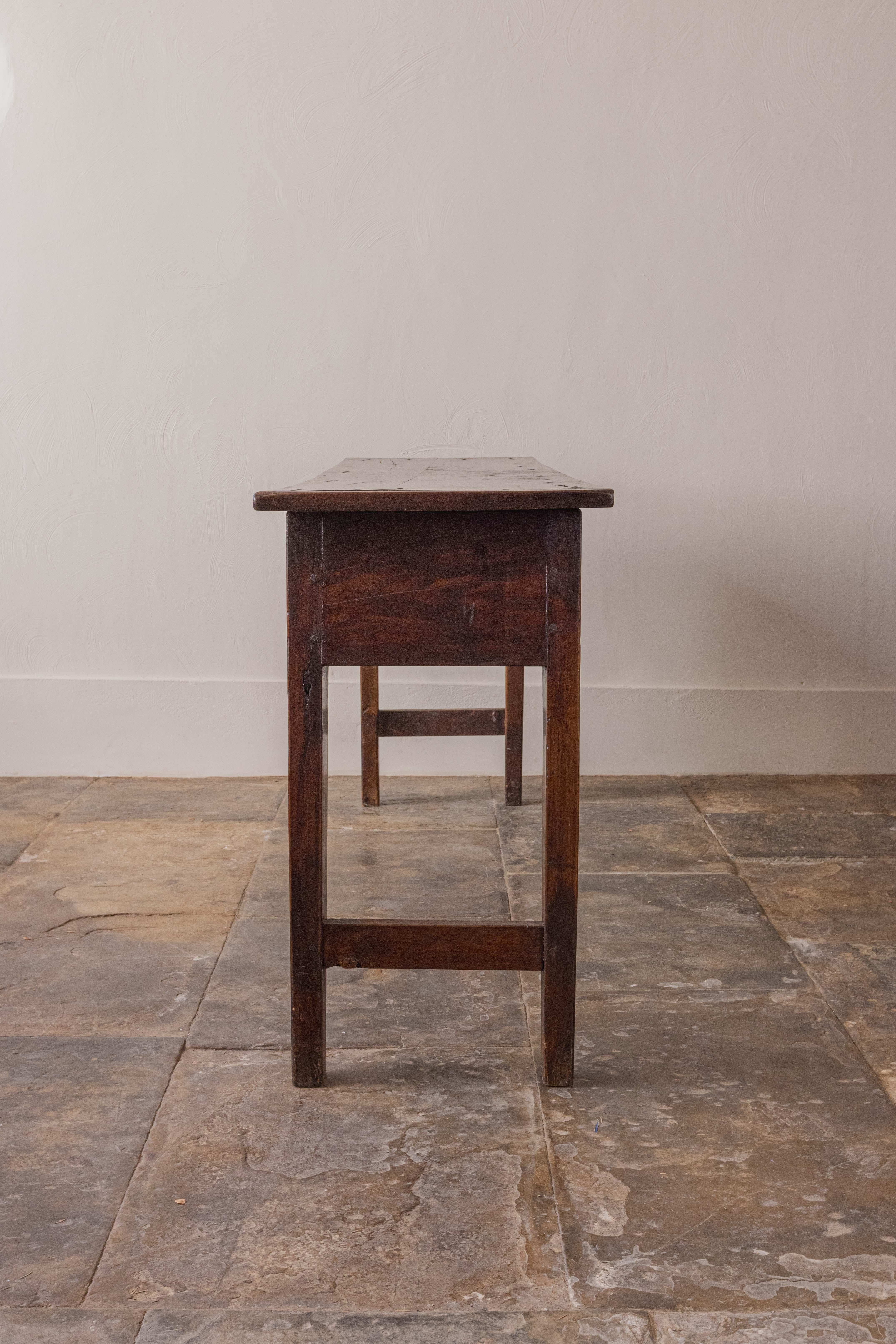 A handsome, late Georgian chestnut dresser base of generous proportions with three drawers and raised on square tapered legs. The drawers are fitted with swan-neck brass handles. Wonderfully narrow, perfect for a hallway, behind a sofa, in a kitchen