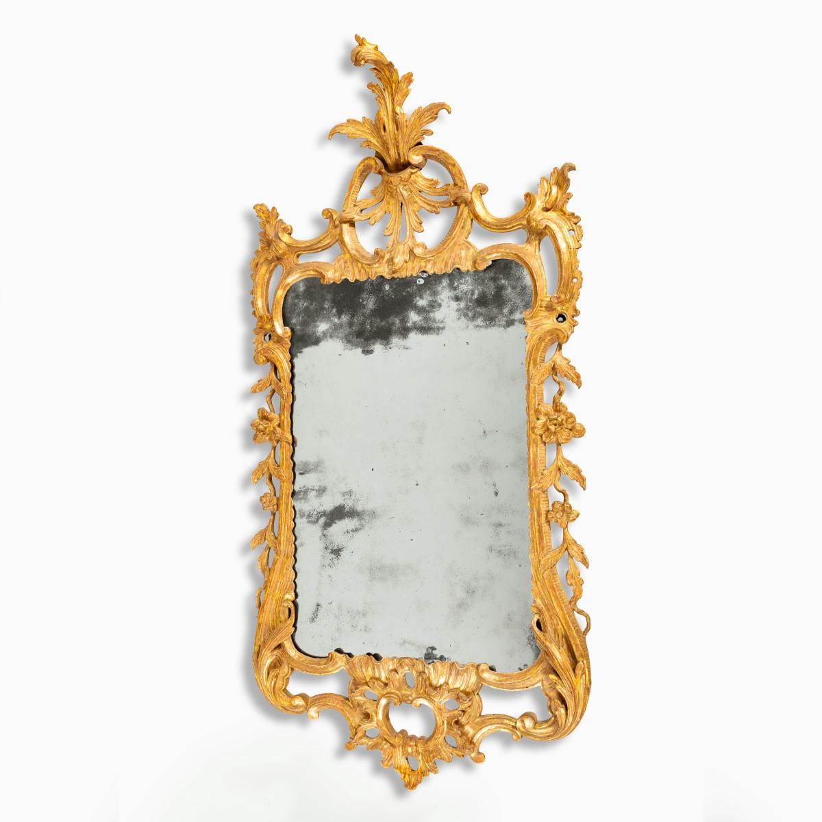 A Georgian Chippendale period gilt-wood mirror, the original rectangular mirror plate with rounded corners within an openwork carved gilt-wood frame comprising rocailles, pendant flowers, C-scrolls and foliage, the cresting with scrolls centred on a