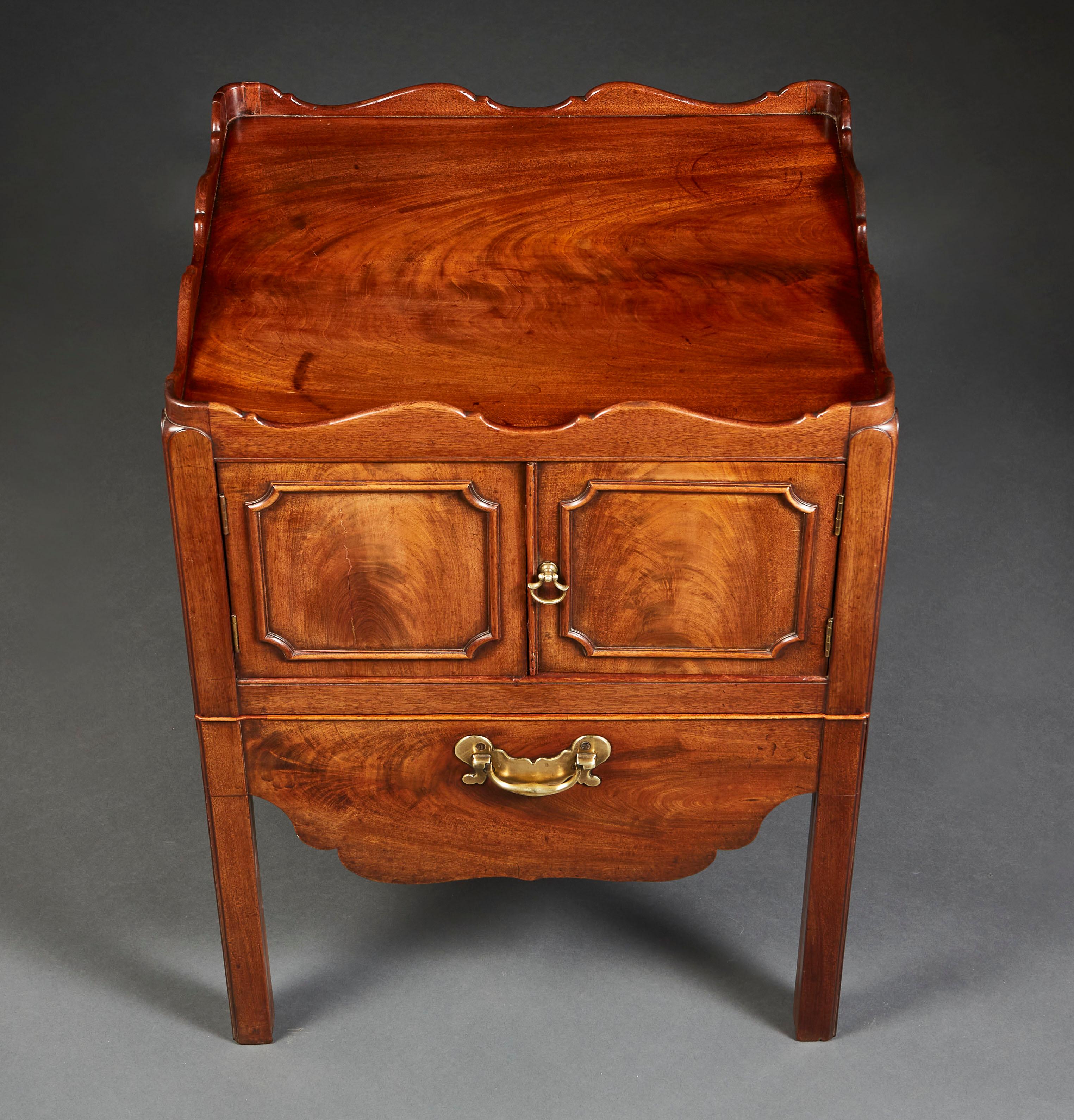 A George III flame mahogany bedside cabinet with flame mahogany timber, opening with two doors and a single drawer to the front, with original brass handles, and undulating gallery to the top.

 