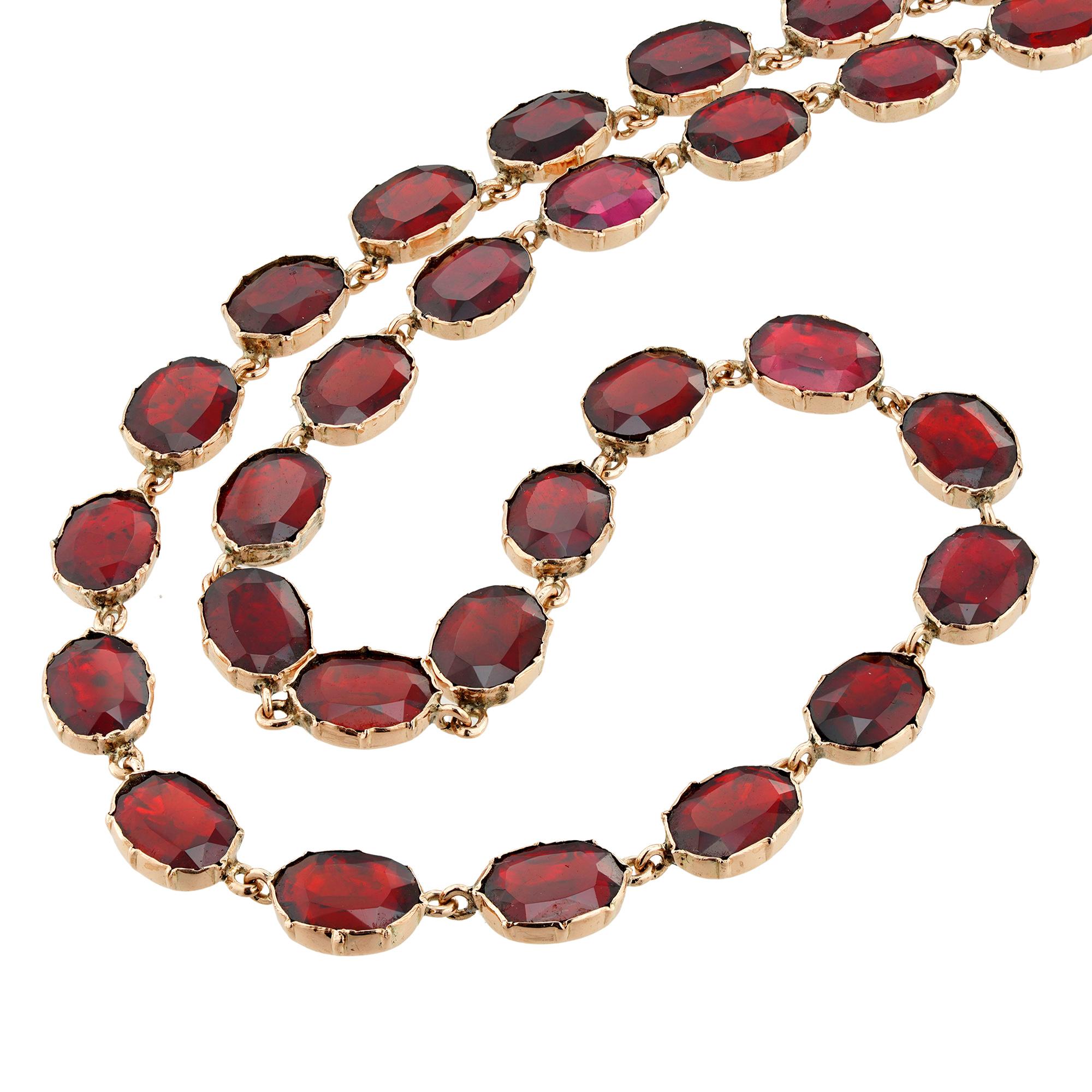 A Georgian garnet riviere necklace, consisting of thirty-five oval-shaped faceted garnets, each individually set in a rose gold cut-down collet with closed back setting, to a hidden clasp and later added safety chain, circa 1800, measuring 40 x