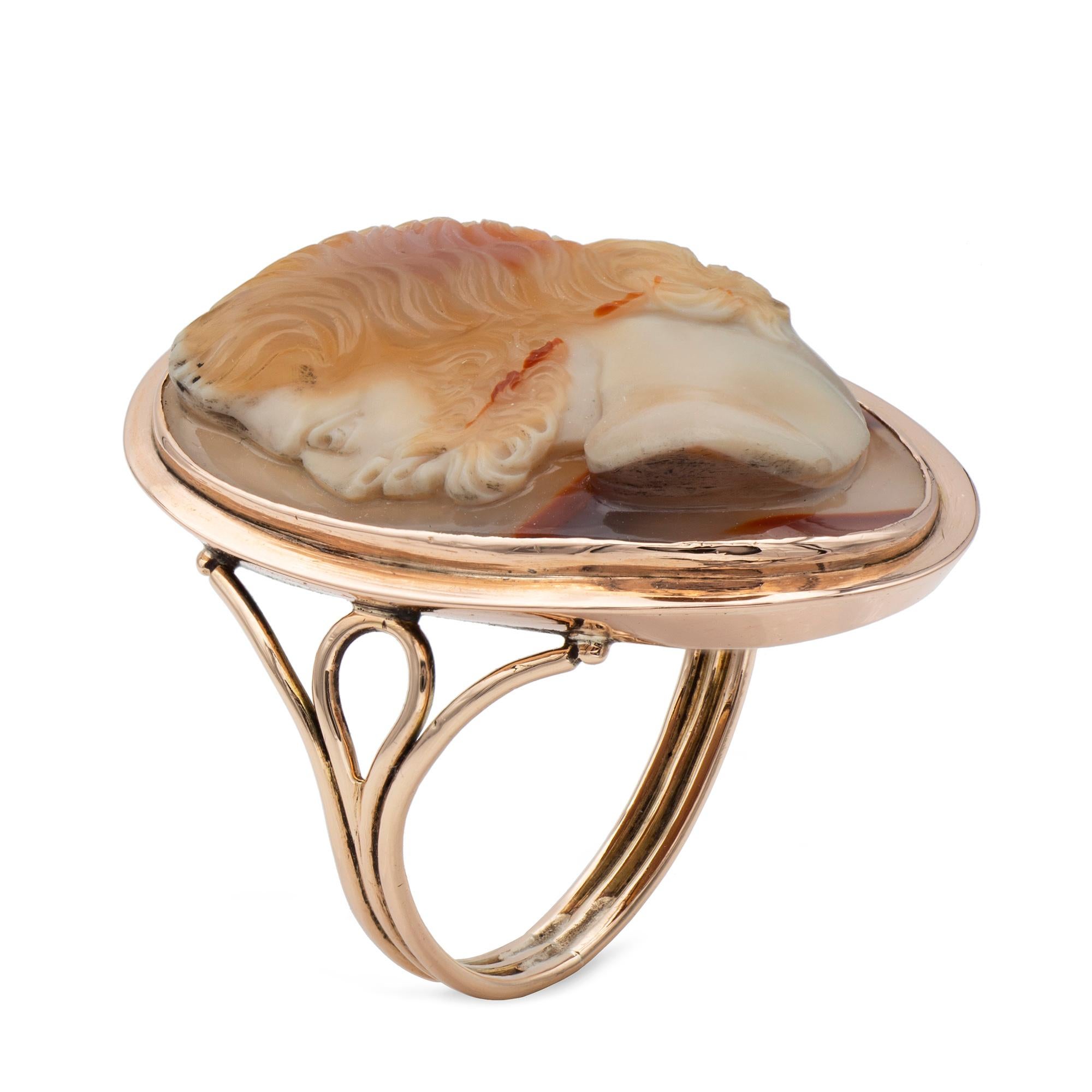 A Georgian hardstone cameo ring, the oval-shaped layered agate cameo, measuring approximately 27 by 17mm, and depicting the finely carved profile of Greek god Zeus (Jupiter), rubover set within a rose gold mount with a ridged detail to the rim, to a