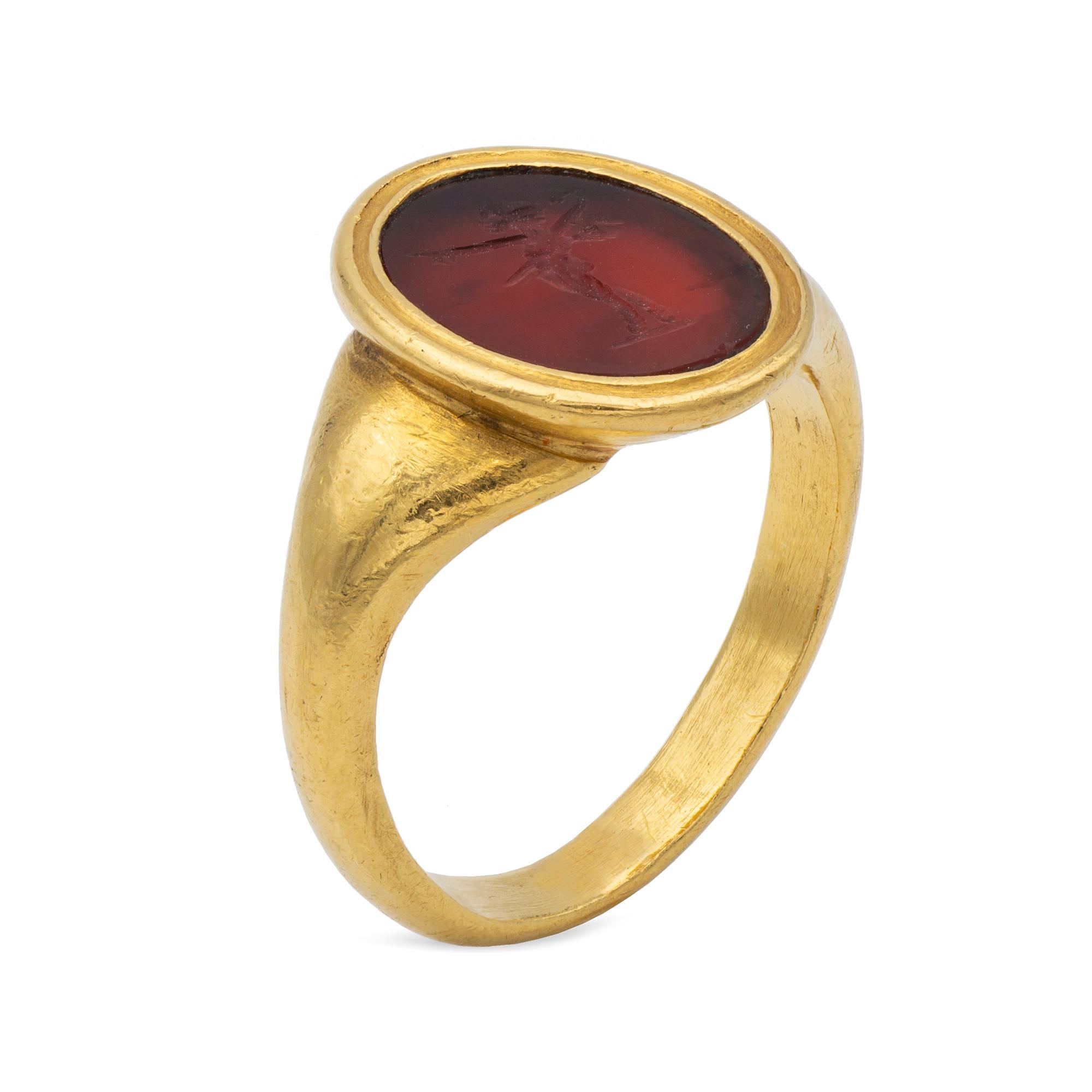 A Georgian hardstone intaglio ring, the oval cornelian measuring 15x11mm, depicting the figure of Pan, rubover set within a yellow gold mount with banded detail to the ridge, to a tapered yellow gold shank, circa 1800, finger size V, gross weight