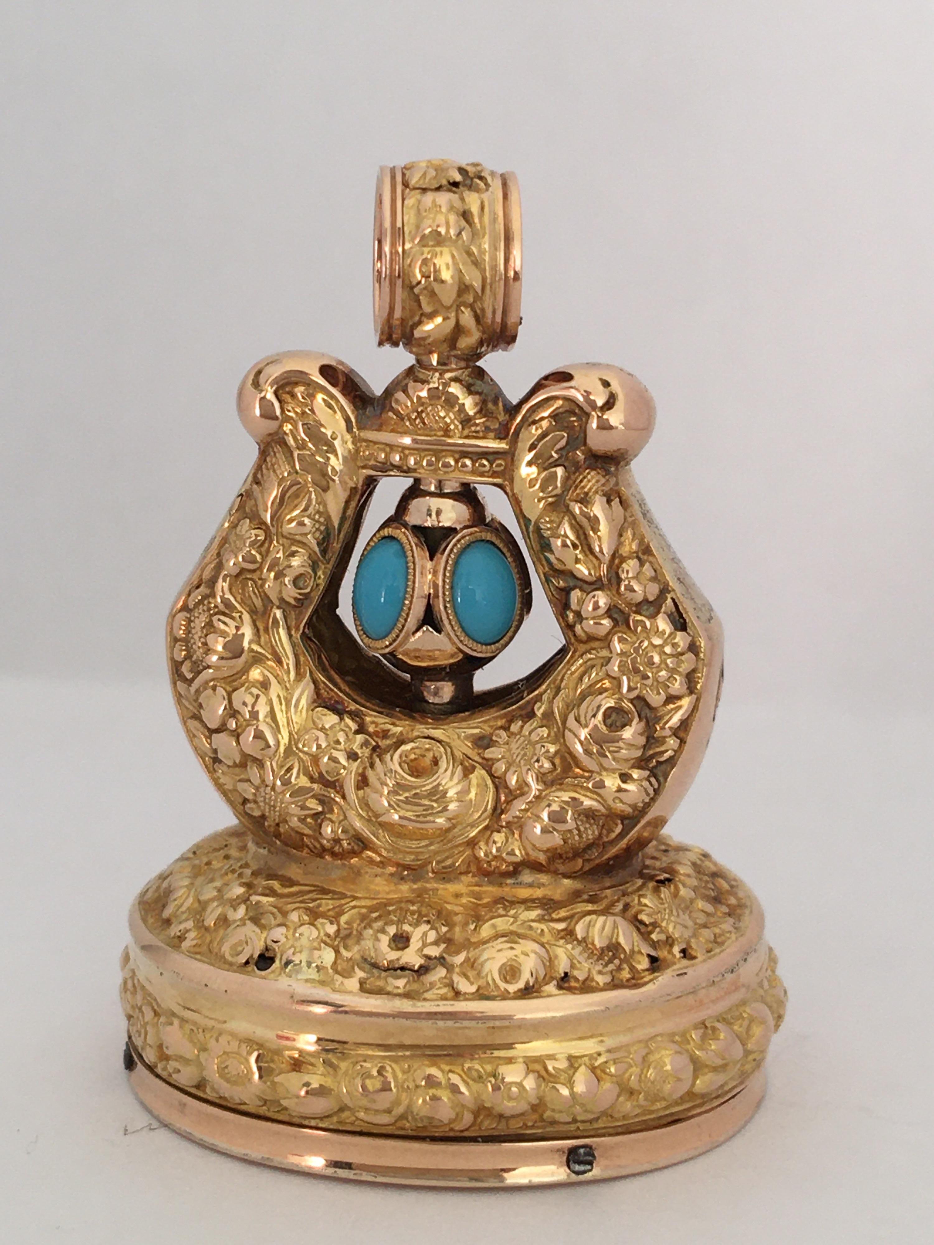 A Georgian gold musical fob seal, oval base with embossed floral motif containing musical mechanism to floral embossed Lyre shaped surmount with fluted oval turquoise bead set winding stem, unmarked test for 22ct with approx. 14ct base. Height