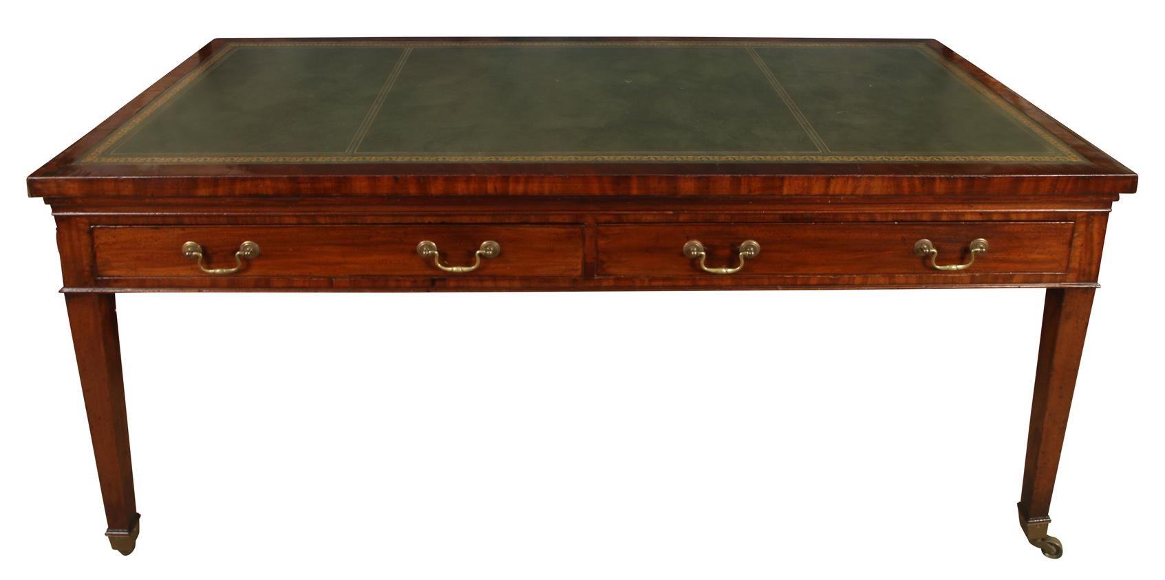 A very handsome Georgian style mahogany desk/writing table with two drawers. The top  has a green tooled leather insert and the tapered legs are raised on castors. The mahogany finish has aged to a wonderful warm patina. Perfect for a library or