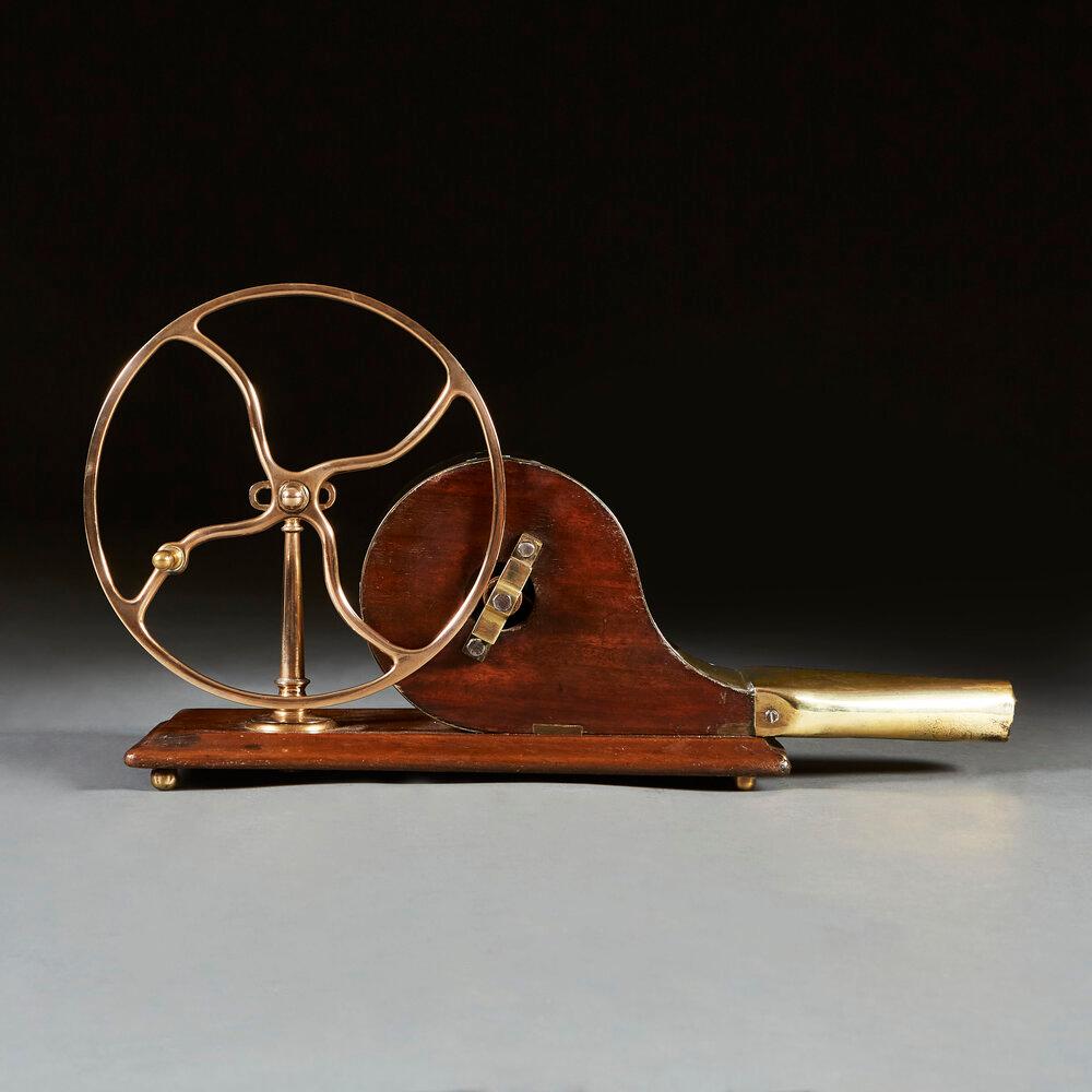 A Georgian brass and mahogany mechanical fire bellows with unusual brass wavy spoked turning wheel and studded brass nose.