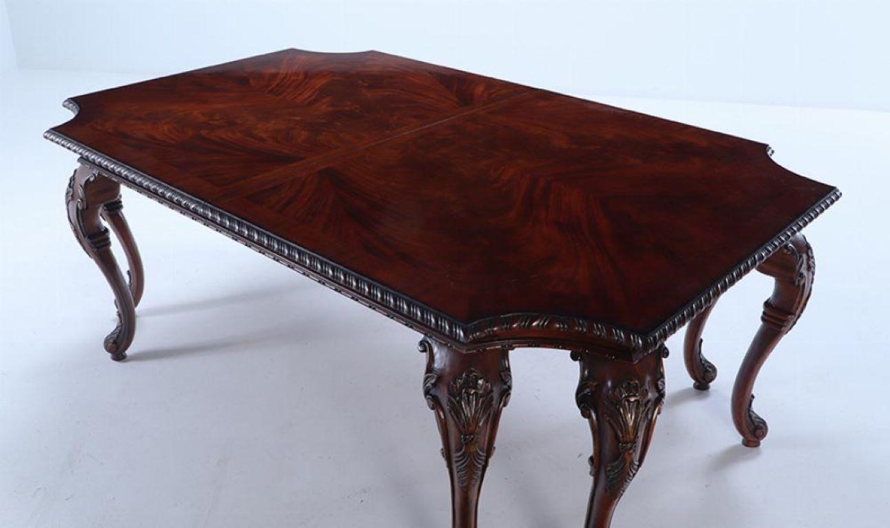 A Georgian style carved mahogany dining table by Century. The flame mahogany and banded top having a carved edge and supported by eight carved legs. Table comes with two large original leaves and table pads. Top extends to 128