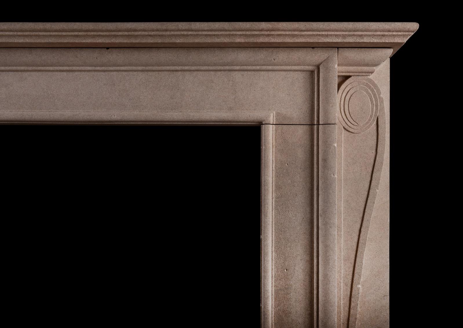 An English Bath stone fireplace in the Georgian style. The shaped jambs  surmounted by elegantly carved scrolls. The plain frieze surmounted by moulded shelf above. A copy of a period original from a property in Mayfair. Part of the Colefax & Fowler