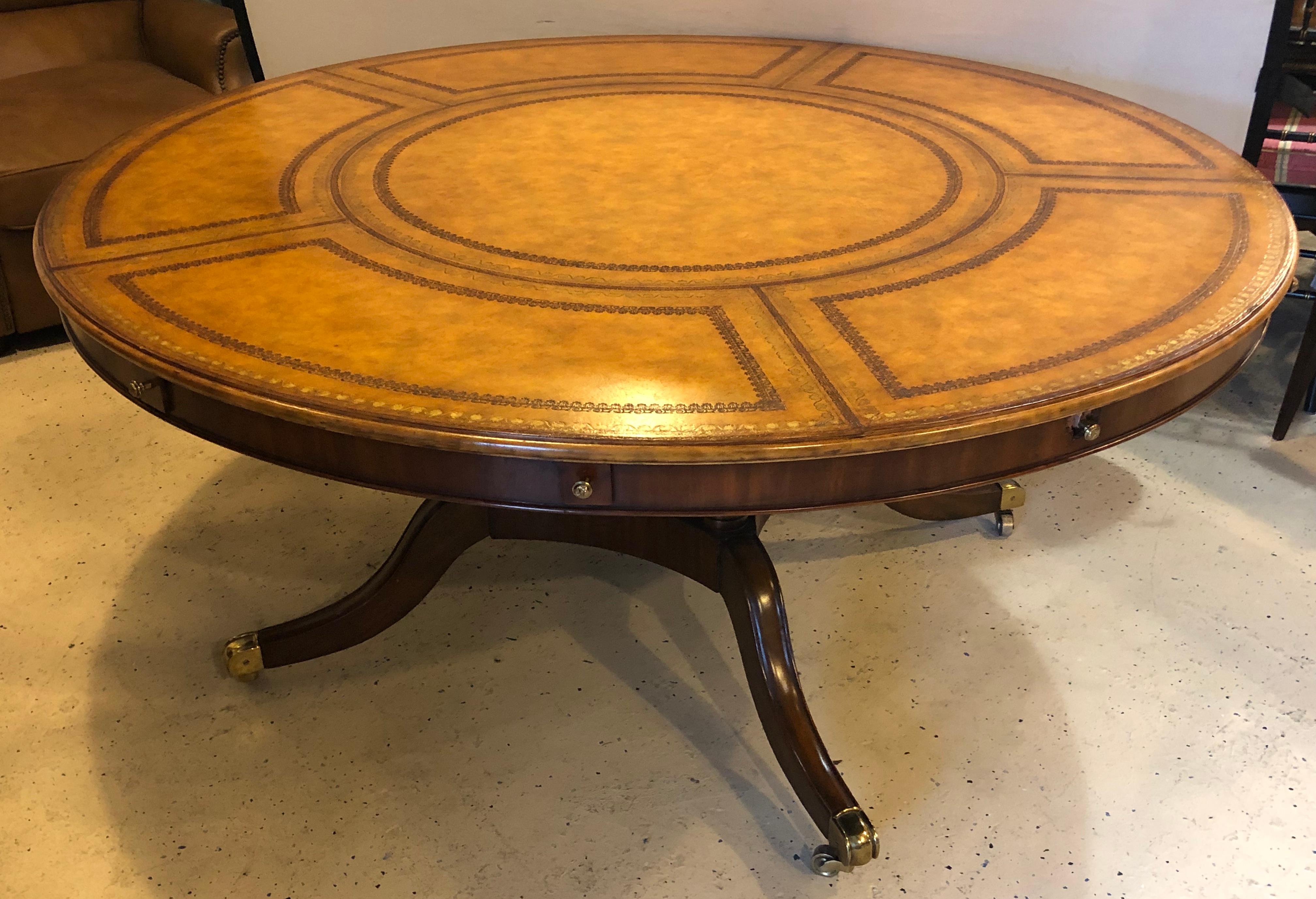 A Georgian style Maitland Smith circular tooled leather top dining, conference or centre table. This fine circular dining table remains round when it is expanded to it full size of 87.5 inches. The finely tooled leather top supported by a quad set