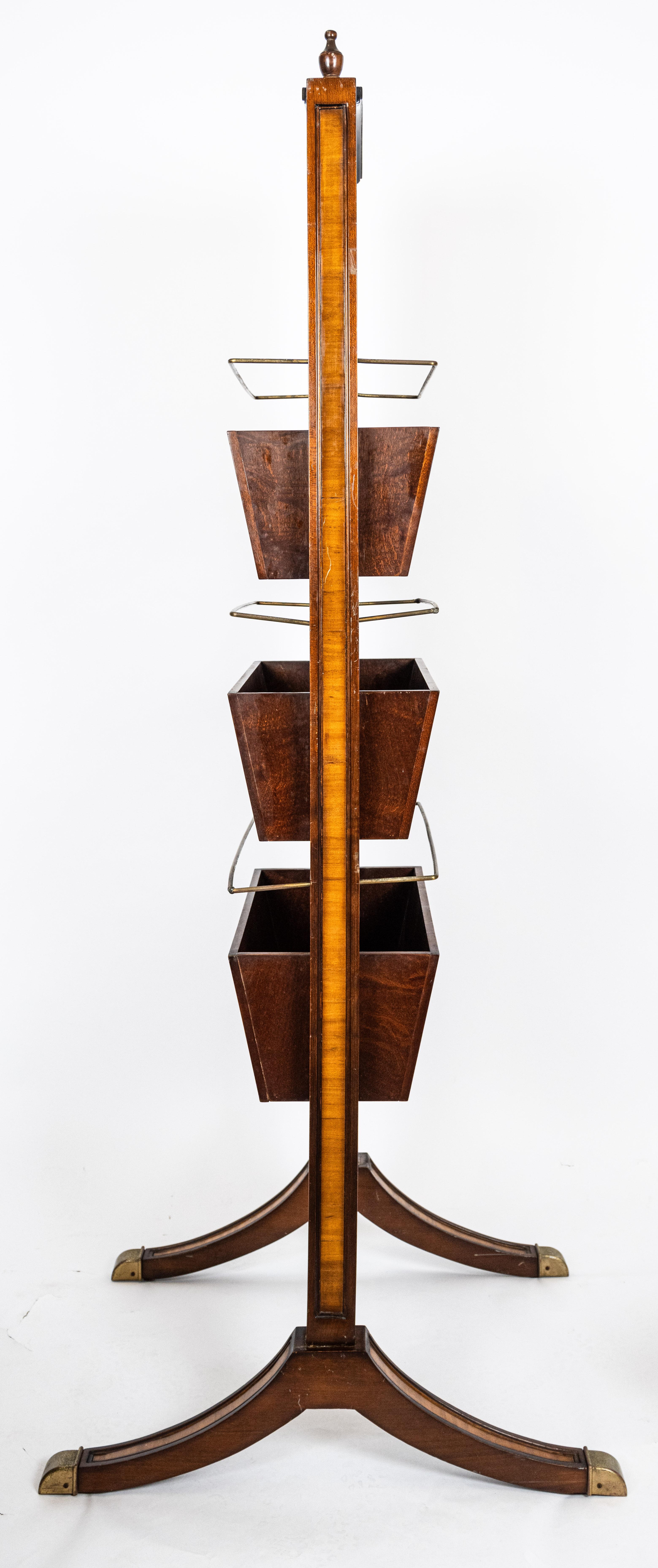 A freestanding Georgian style mahogany and mahogany veneered stand. Each side with wooden pockets below four brass newspaper rails. Designed for the display of newspapers and magazines. The vertical rectangular form with an arched top, molded edges,