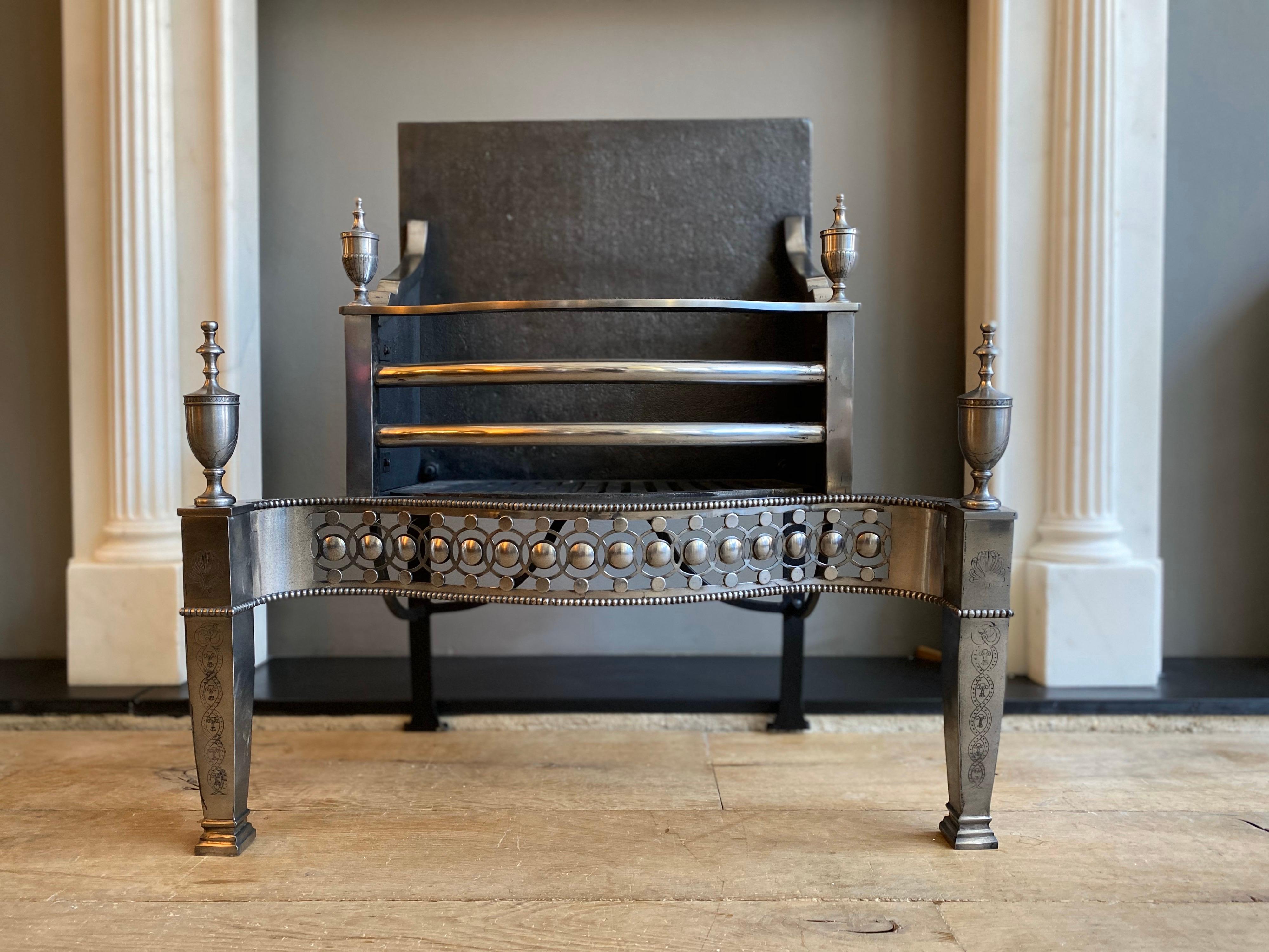 An 18th century style fire grate in polished steel, with worked serpentine fret, engraved column supports and square fire back. A good quality copy of an earlier piece.
