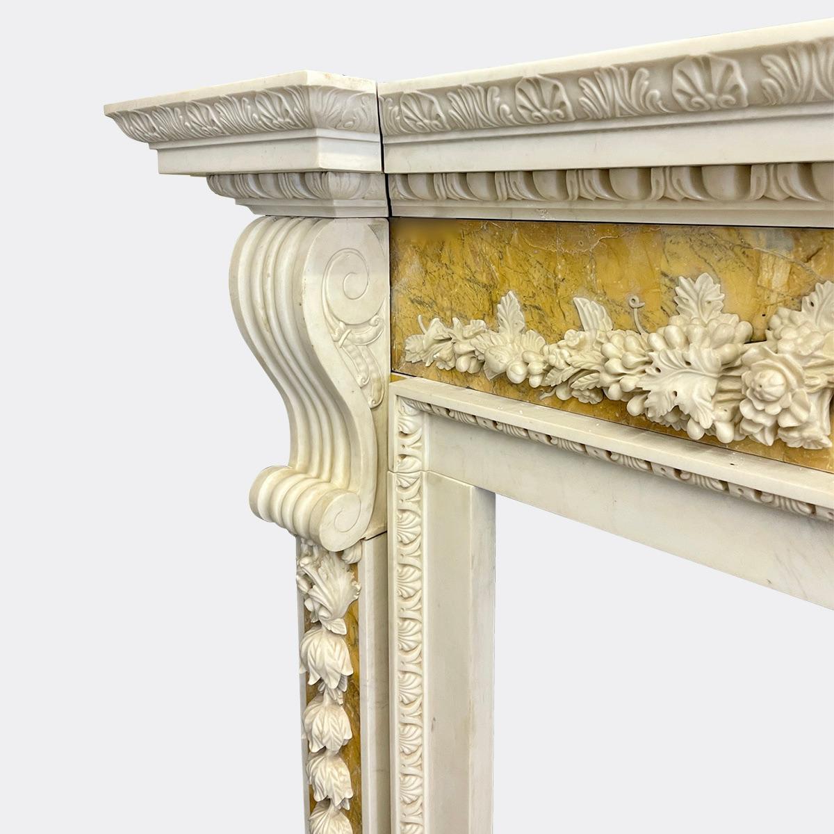 A substantial Palladian style fireplace in White and Siena Marbles. The 3 piece breakfront shelf with Acanthus and Egg and Dart mouldings, the Siena frieze below with carvings applied in white marble of Urn and vines, the jambs with large corbels
