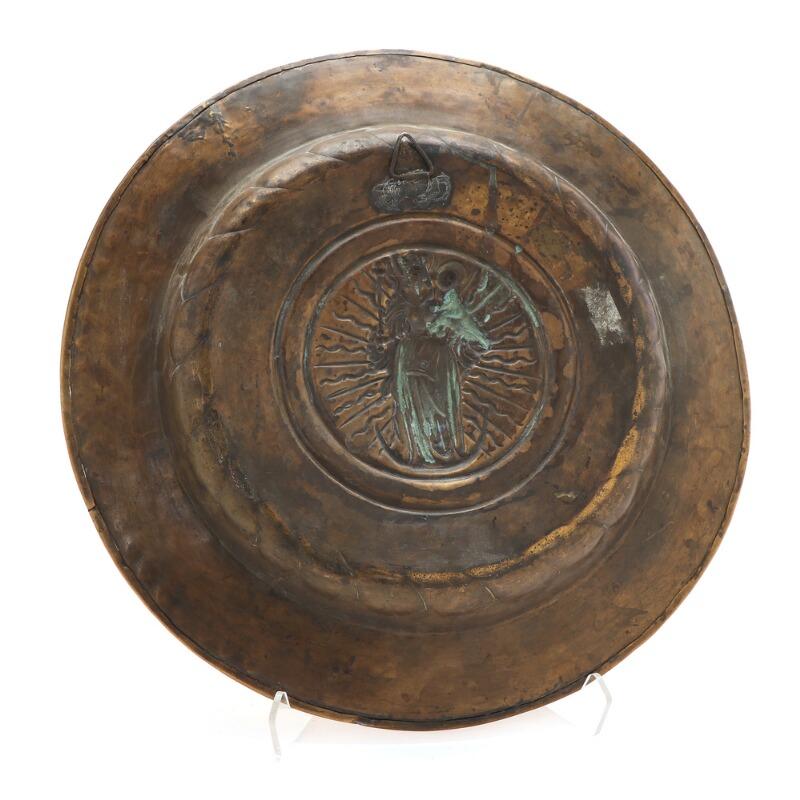 A German 16th-17th century embossed and chiseled brass baptismal basin adorned with Virgin Mary standing on a crescent moon and (unreadable) text, probably Nuremberg. The basin features the Holy Mother with her Child and they are encircled by an old