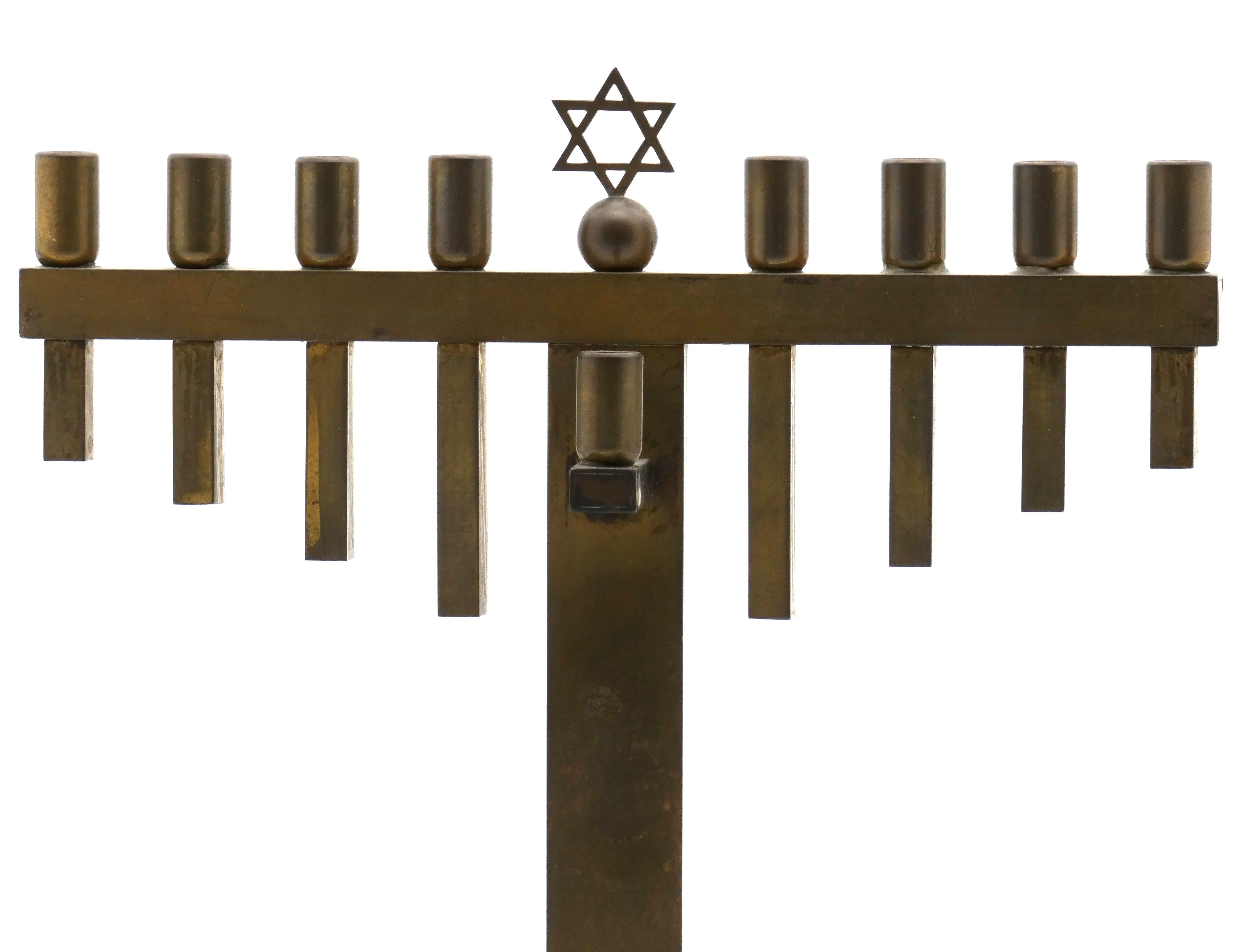 The German brass menorah displayed is an exemplary sample of the Art Deco age, with its cylindrical and defined structural shapes and craftsmanship.

Menorah stands on a flat base with arched split pipes formed from its base on either side. 

Three