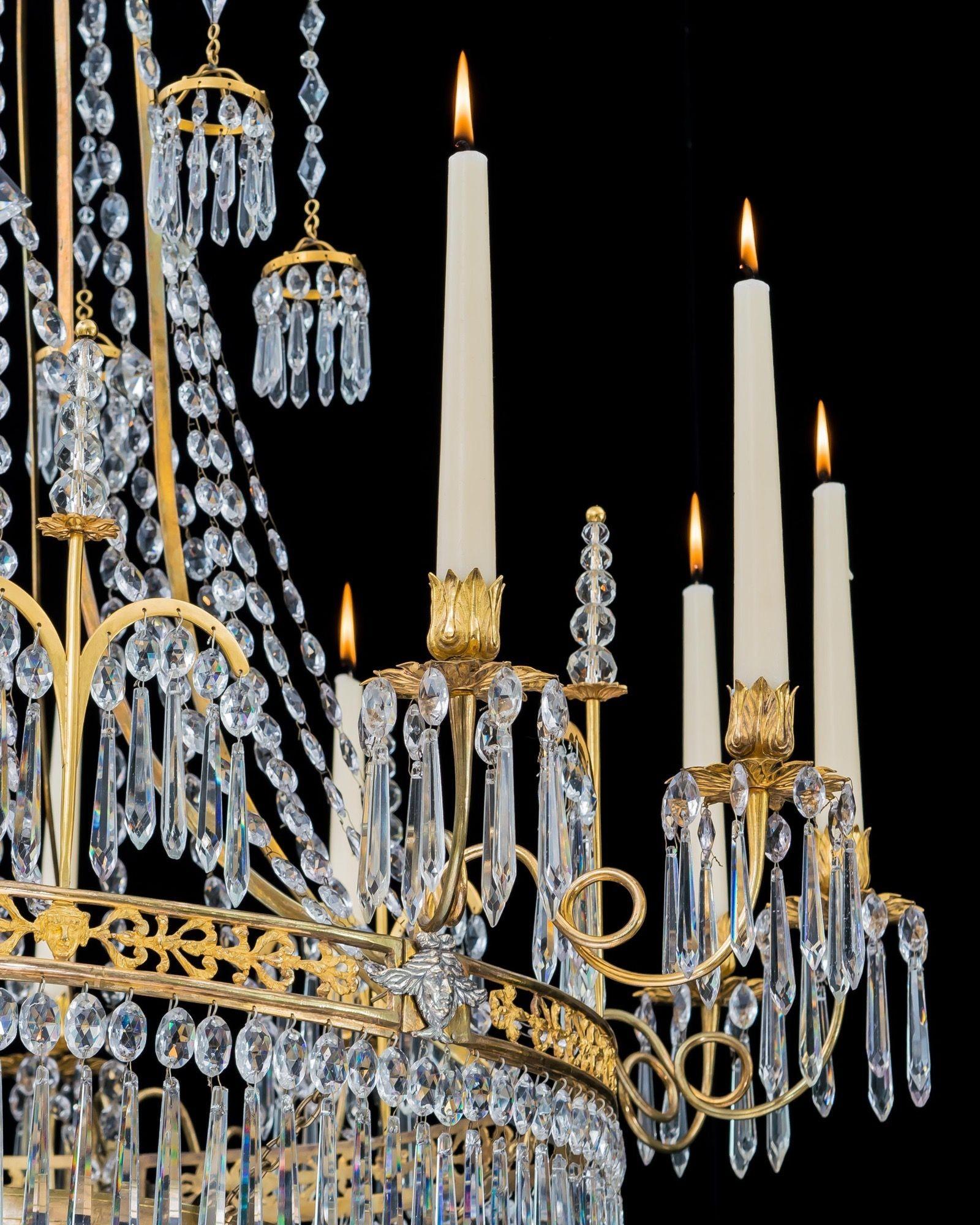 Un élégant lustre en bronze doré avec une couronne suspendue entrelacée de perles à facettes, supportant six glands en bronze doré suspendus à des chaînes de diamants. Le cadre principal orné, monté avec des mofits en argent, émet douze bras à