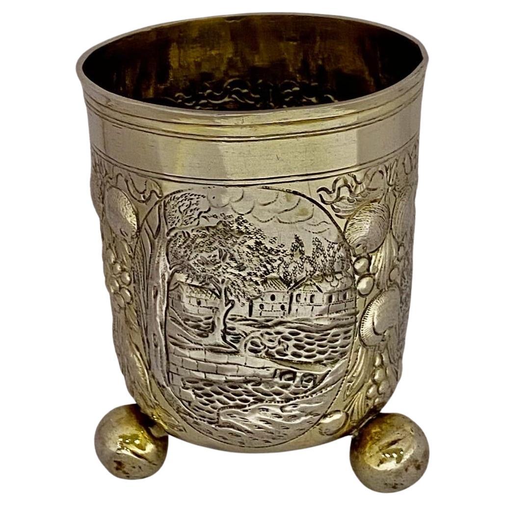 A high quality beaker embossed with three oval cartouches depicting architectural scenes and swags of fruit suspended from ribbon-bows, on three ball feet. weight 90 grams. This is a superb antique German sterling silver beaker measuring 3.6” (12