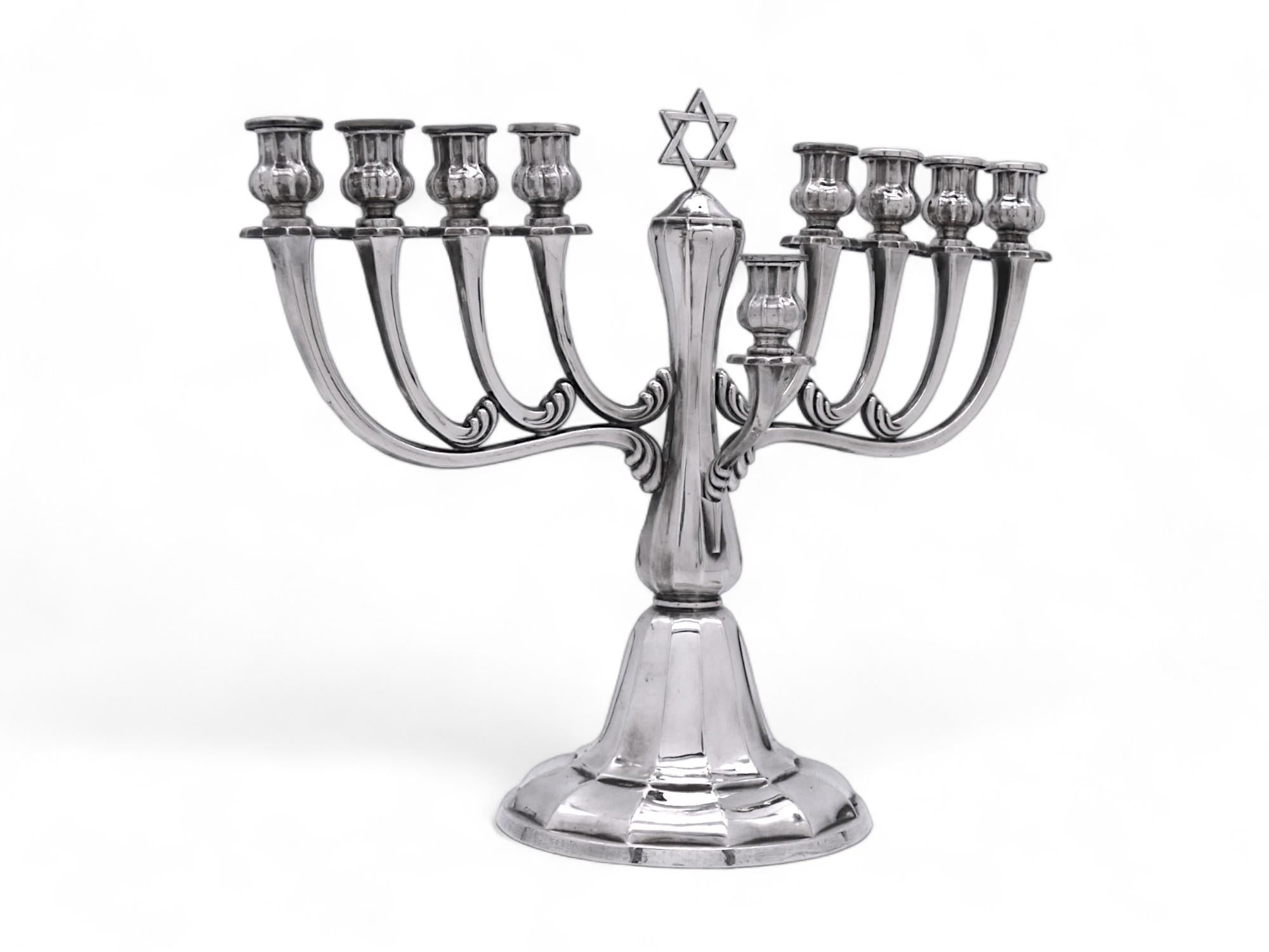 Una splendida Menorah di Hanukkah realizzata da Gayer & Krauss all'inizio del XX secolo.

Poggia su una grande base a cupola sfaccettata a gradini, con fondo a campana e centro a rocchetto e ponderata. Il gambo continua ad alzarsi in modo simile e