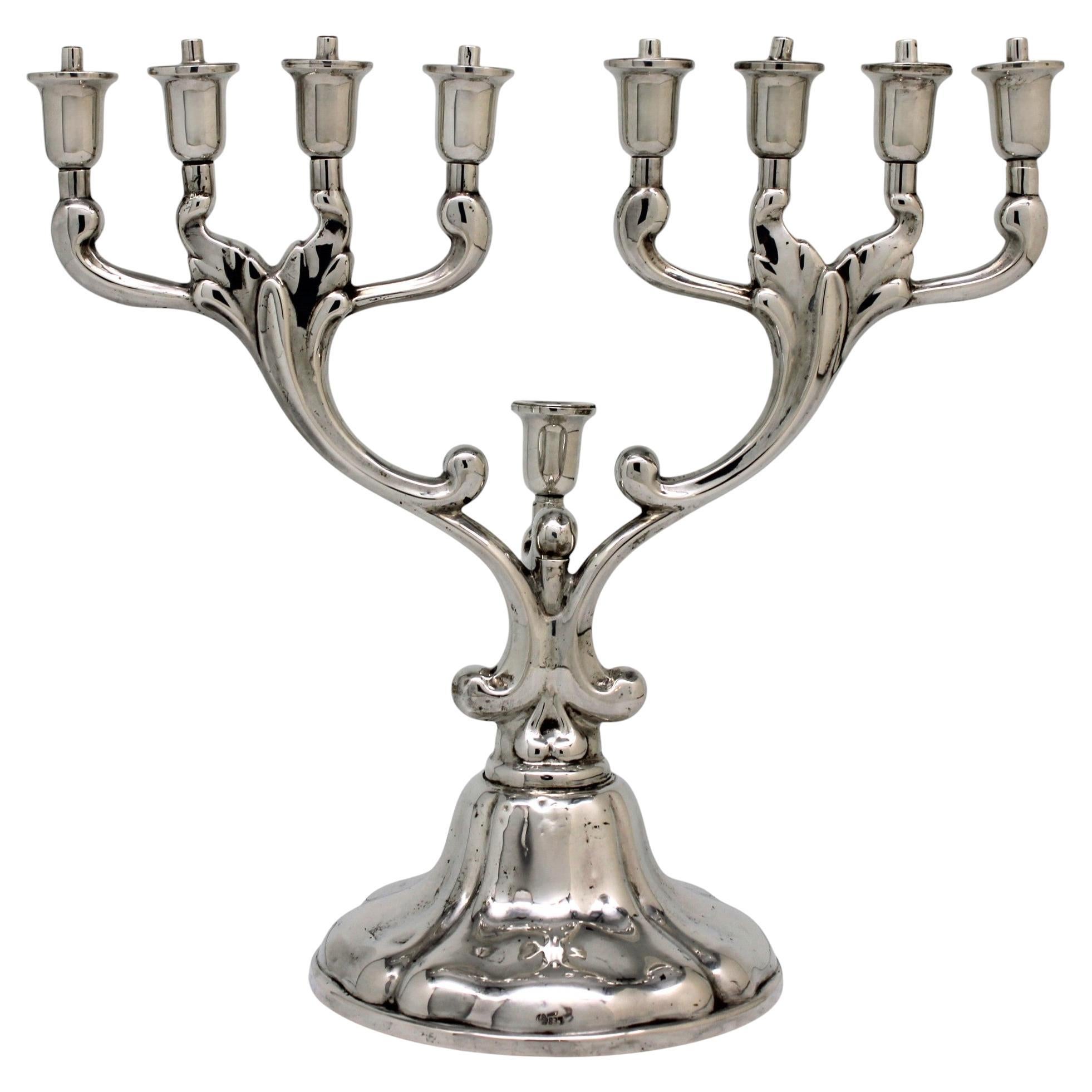 An exquisite Hanukkah lamp, crafted in German silver circa 1950, showcases a beautifully intricate design inspired by the organic form of tree branches. Its gracefully curved arms extend symmetrically from a central stem, creating a striking and