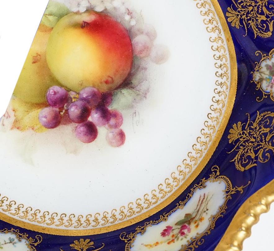 A Stunning Royal Worcester Dessert Service, circa 1915. Each piece hand painted with an arrangement of fruits, signed by G.H Cole, inside a cobalt blue border reserved with gilt-framed flower panels. In between these floral panels are richly gilded