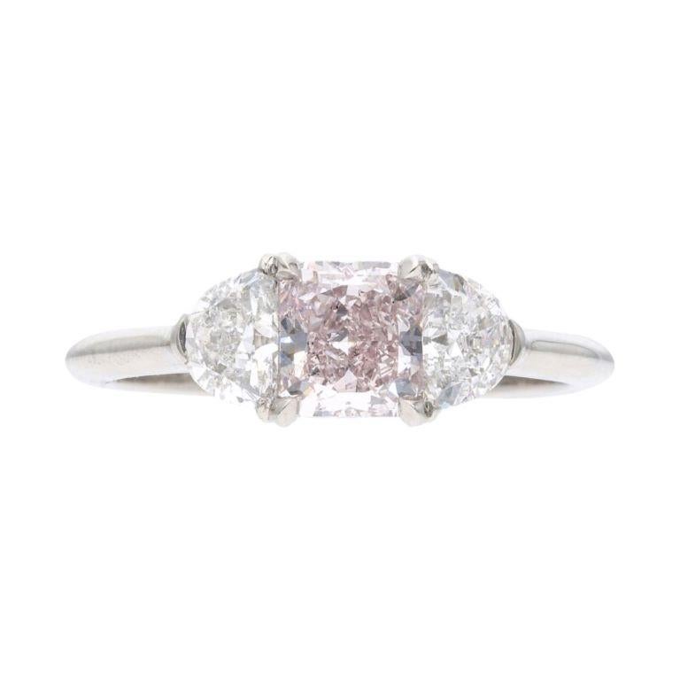 Centering a radiant cut fancy pink diamond, flanked by 2 half-moon diamonds. 
- Pink diamond weighs 0.75 carat
 - Half-moon diamonds weighing a total of approximately 1.00 carat
 - Platinum
 - Total weight 3.83 grams
 - Size 6 
- Accompanied by GIA