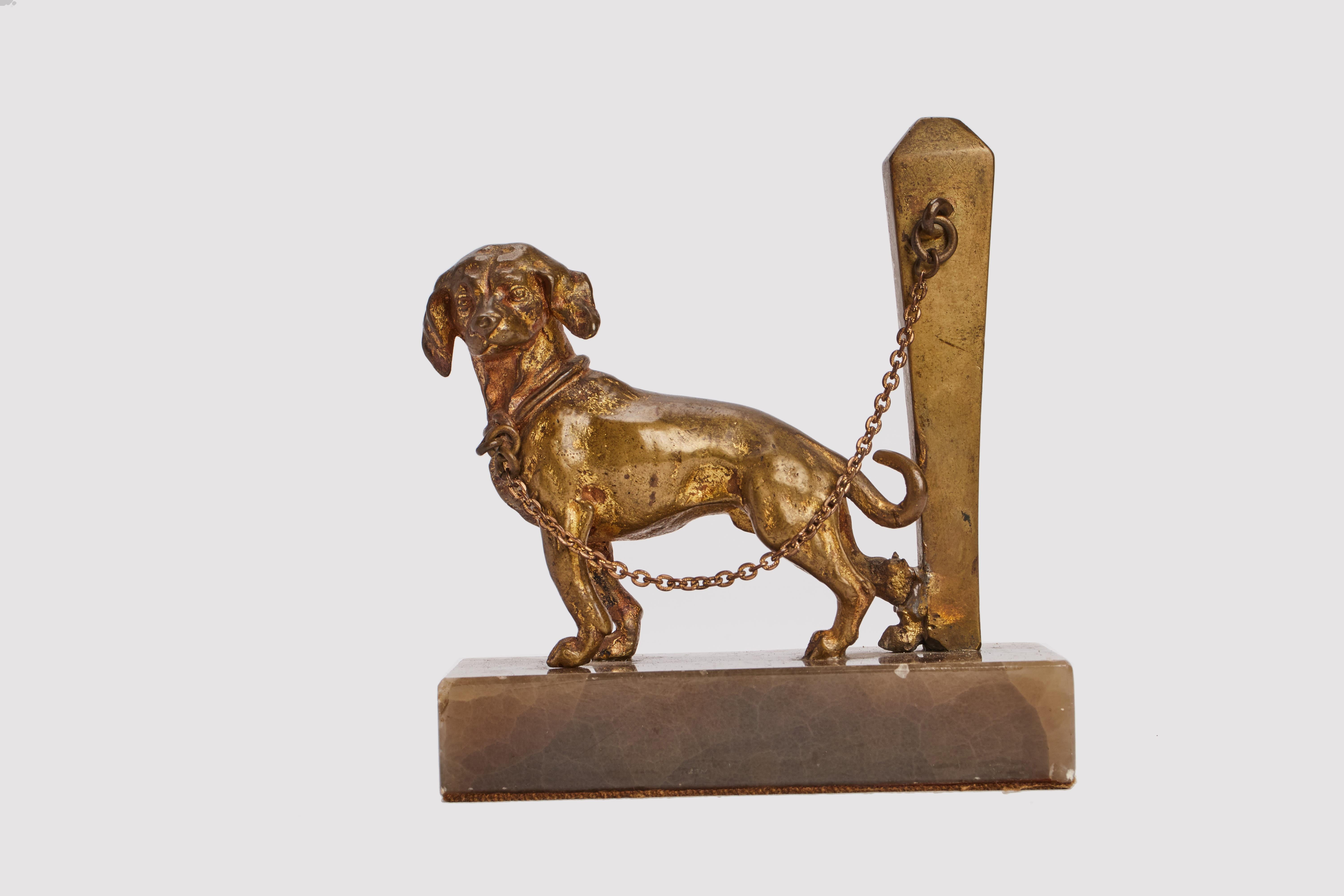 Petite sculpture en bronze doré représentant un chien enchaîné. Base en marbre. France vers 1890.  