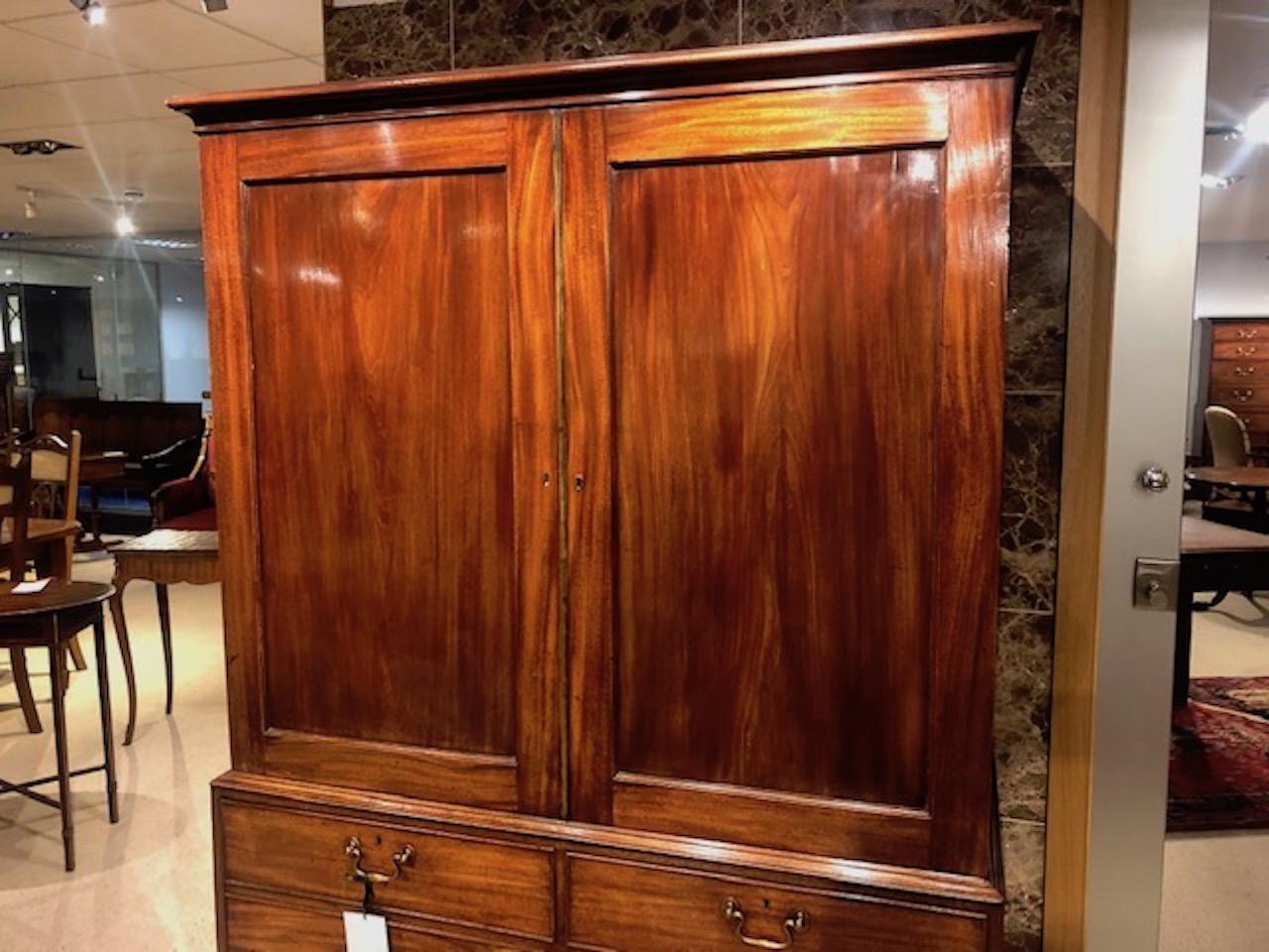 A Georgian period Gillows of Lancaster mahogany linen press. The upper section having a moulded cornice above two wonderful Cuban mahogany panelled doors, opening to reveal four oak lined slides retaining their original blue paper linings, typical