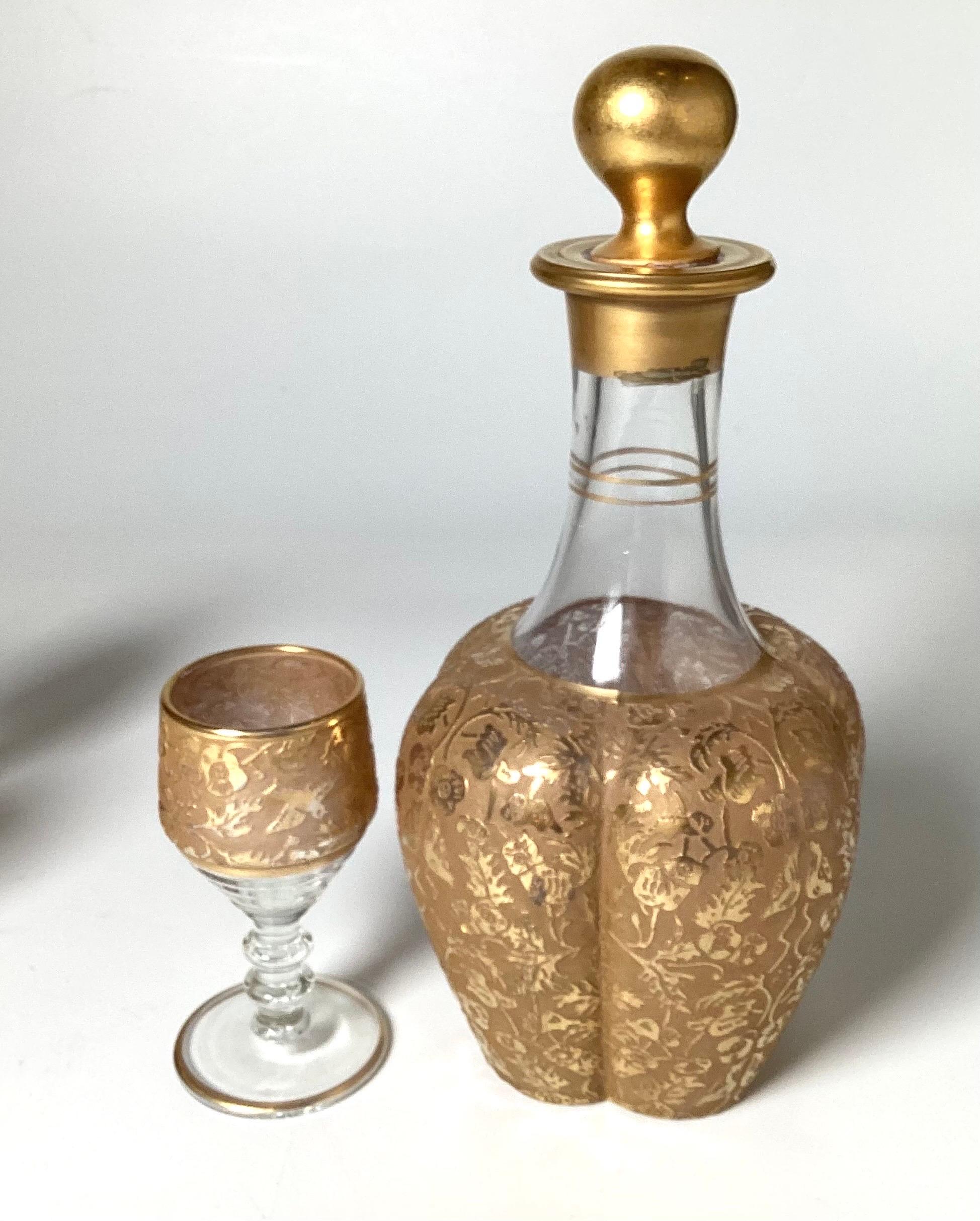 A gilt and engraved glass cordial decanter set. The decanter with original stopper with 5 cordial glasses. All with engraved decoration with heavy gilt trim.