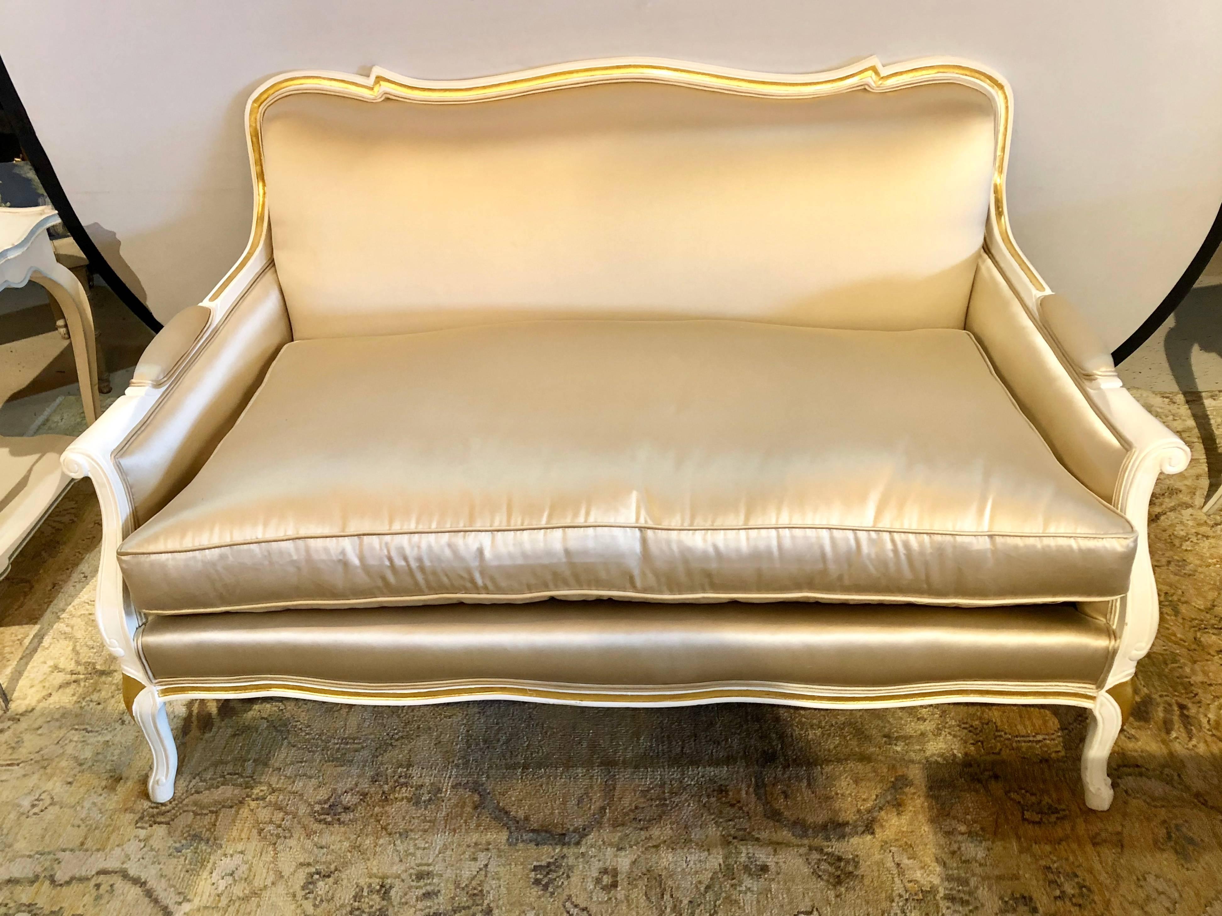 A gilt and paint decorated settee / loveseat in a fine satin upholstery. In this Louis XV style this fine Hollywood Regency sofa is as stylish as one could possible dream of. The finely custom upholstered sofa having two matching cushions. Directly